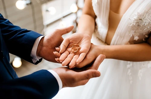 Bagues de mariage posées dans les mains.