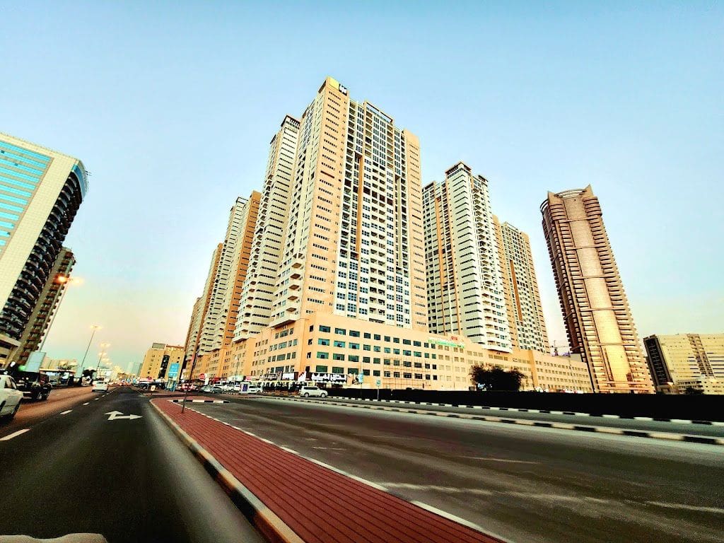 Wide-angle view of the towers from the main road. High-visibility residential landmark in the heart of Ajman.