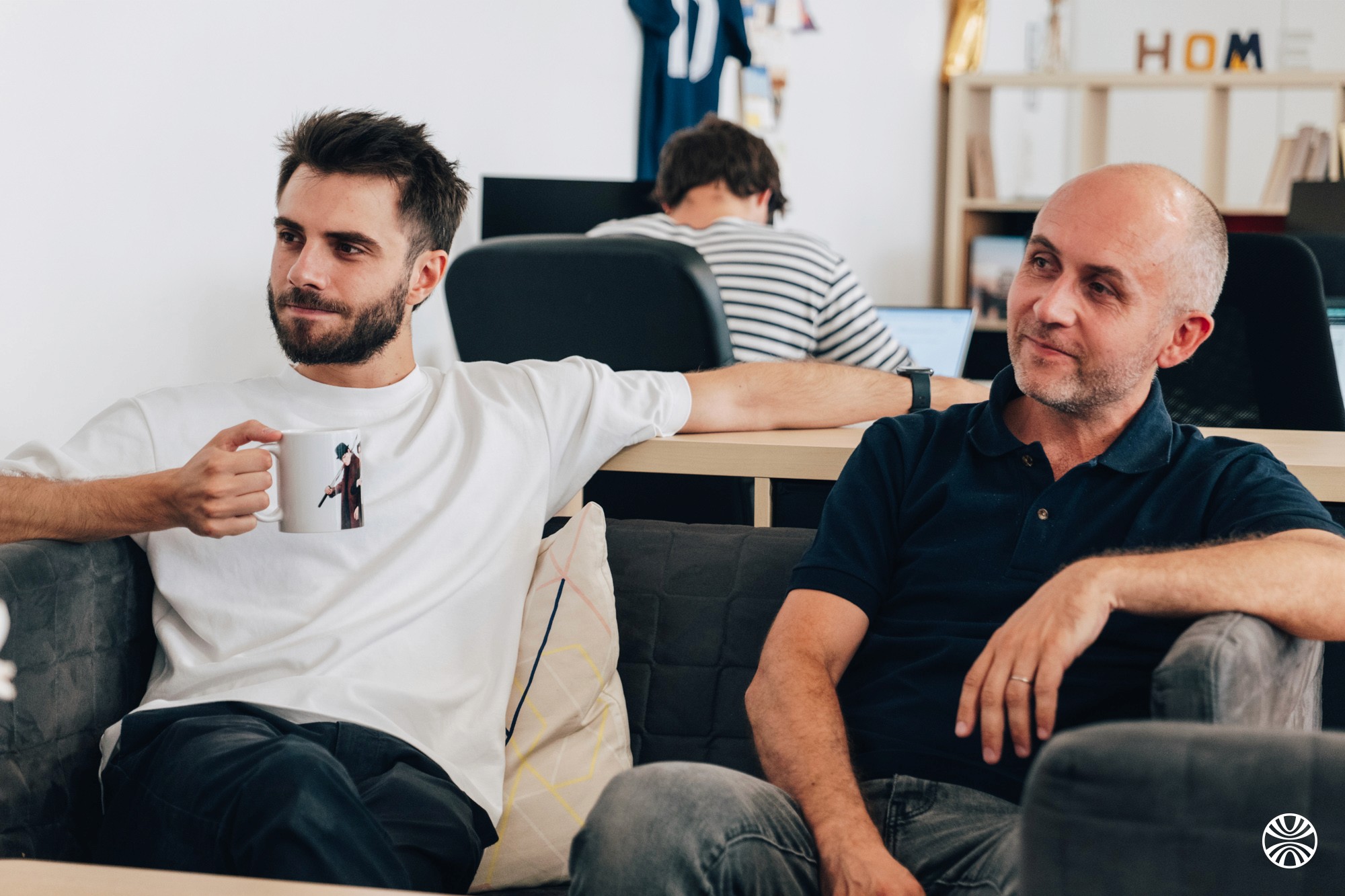 Photo de 2 seveners : Alex et Thomas dans un canapé, un café à la main.