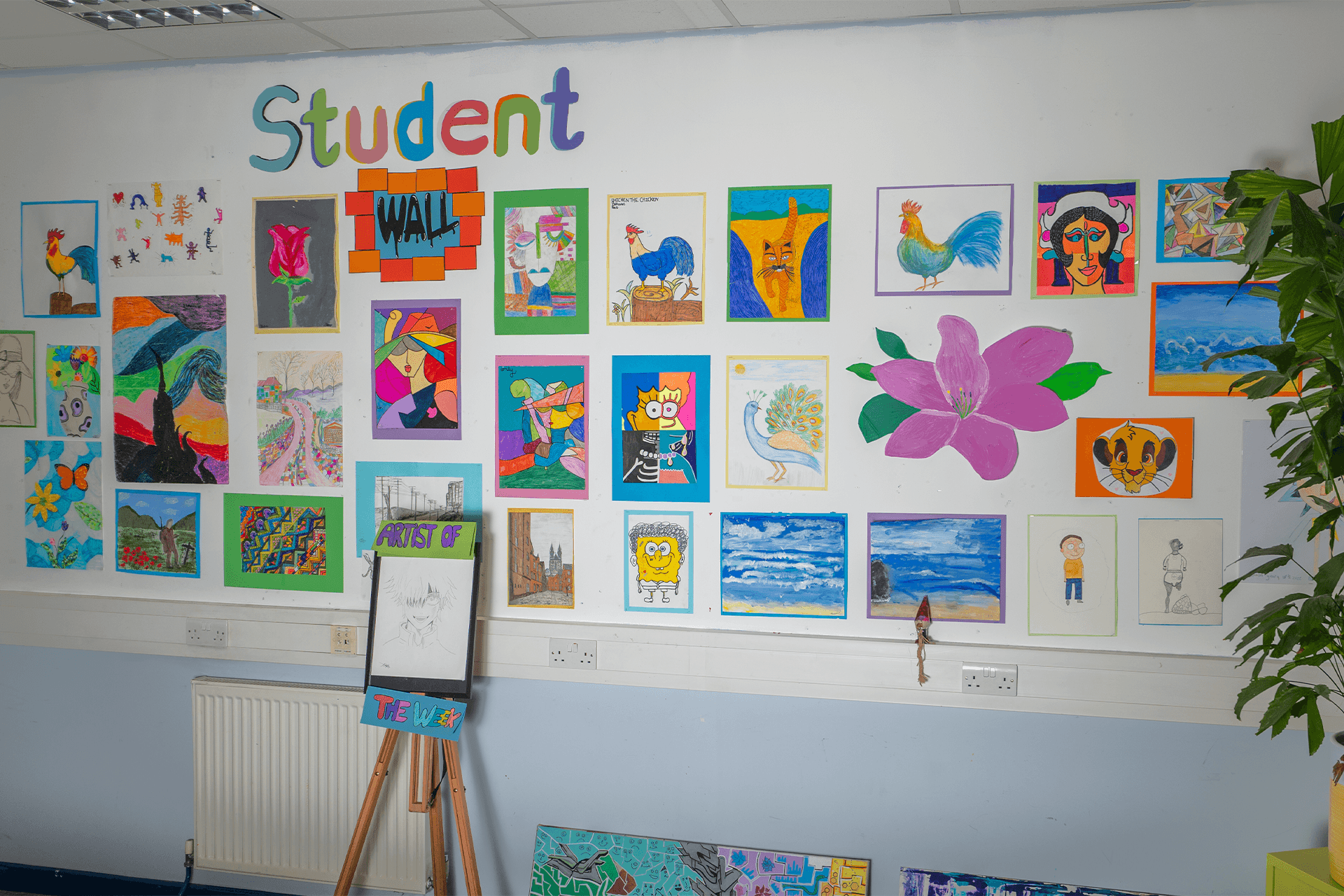 Bulletin board decorated with colorful drawings and artwork created by students, displayed in the school hallway