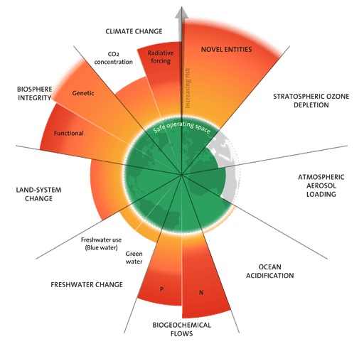A young person with curly hair smiles at the camera while sitting in front of a laptop against a dark background.