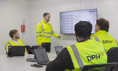 Entrance of a modern glass building with illuminated facade and reflections