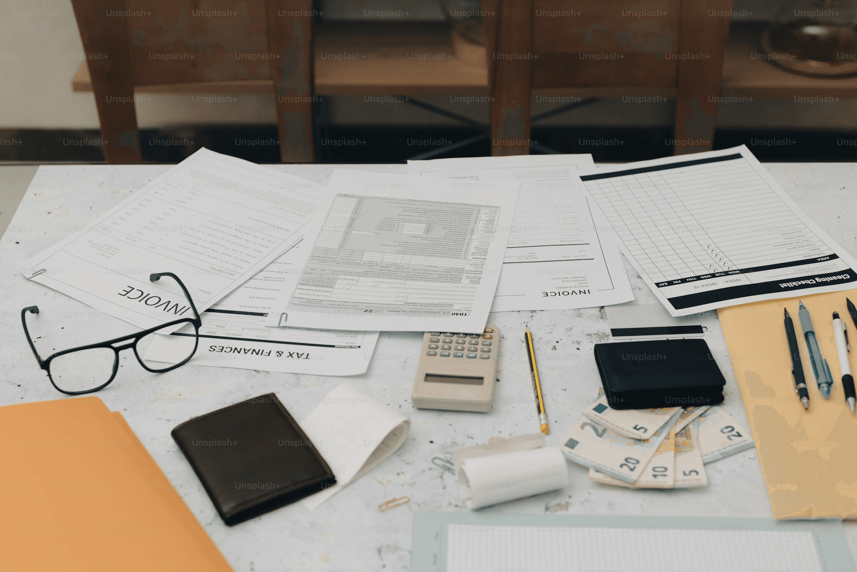 Desk with stacked documents, folders, and a calculator in a home office