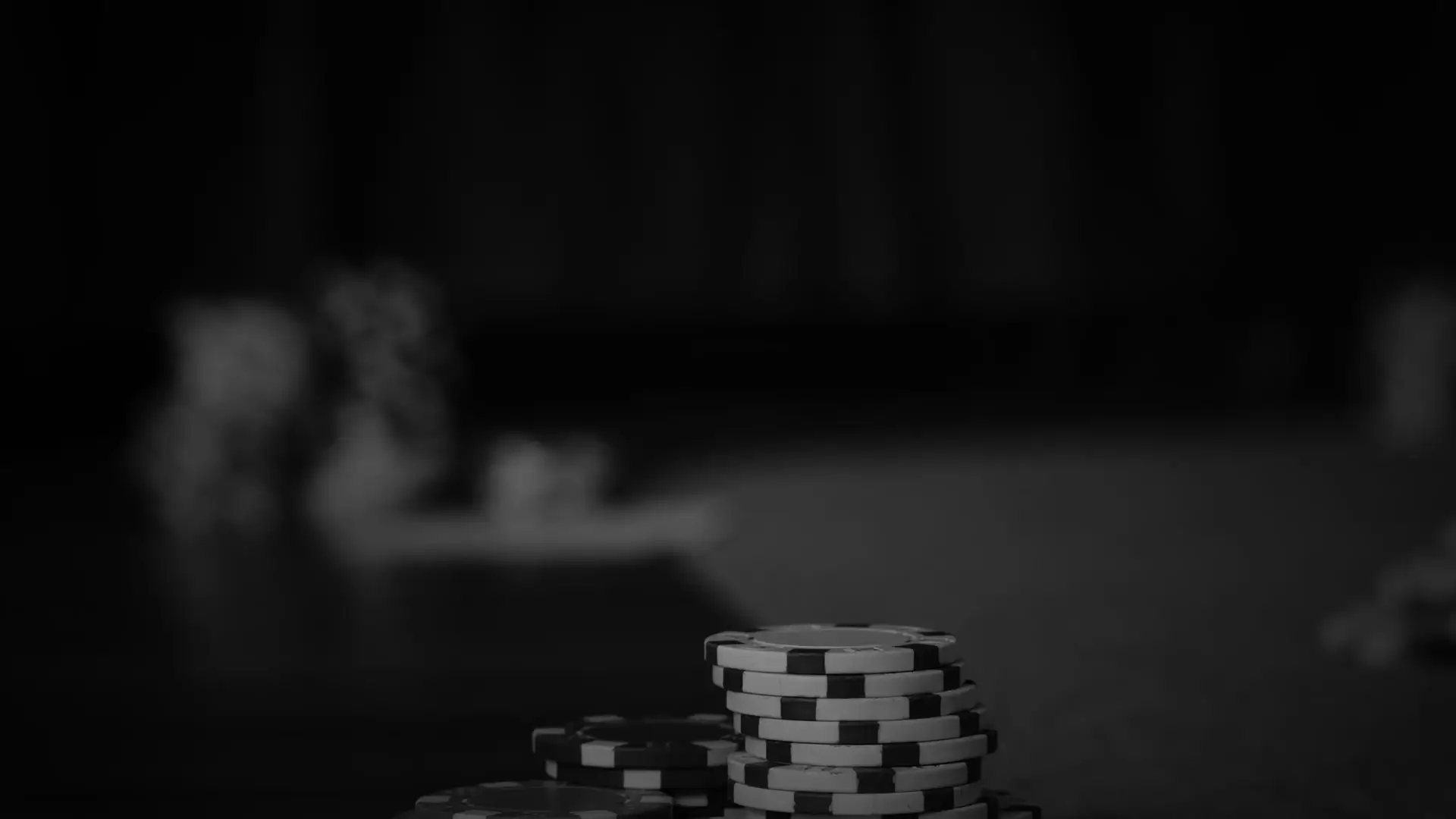 A black and white photo graph of a close up view of a poker table with stacks of chips