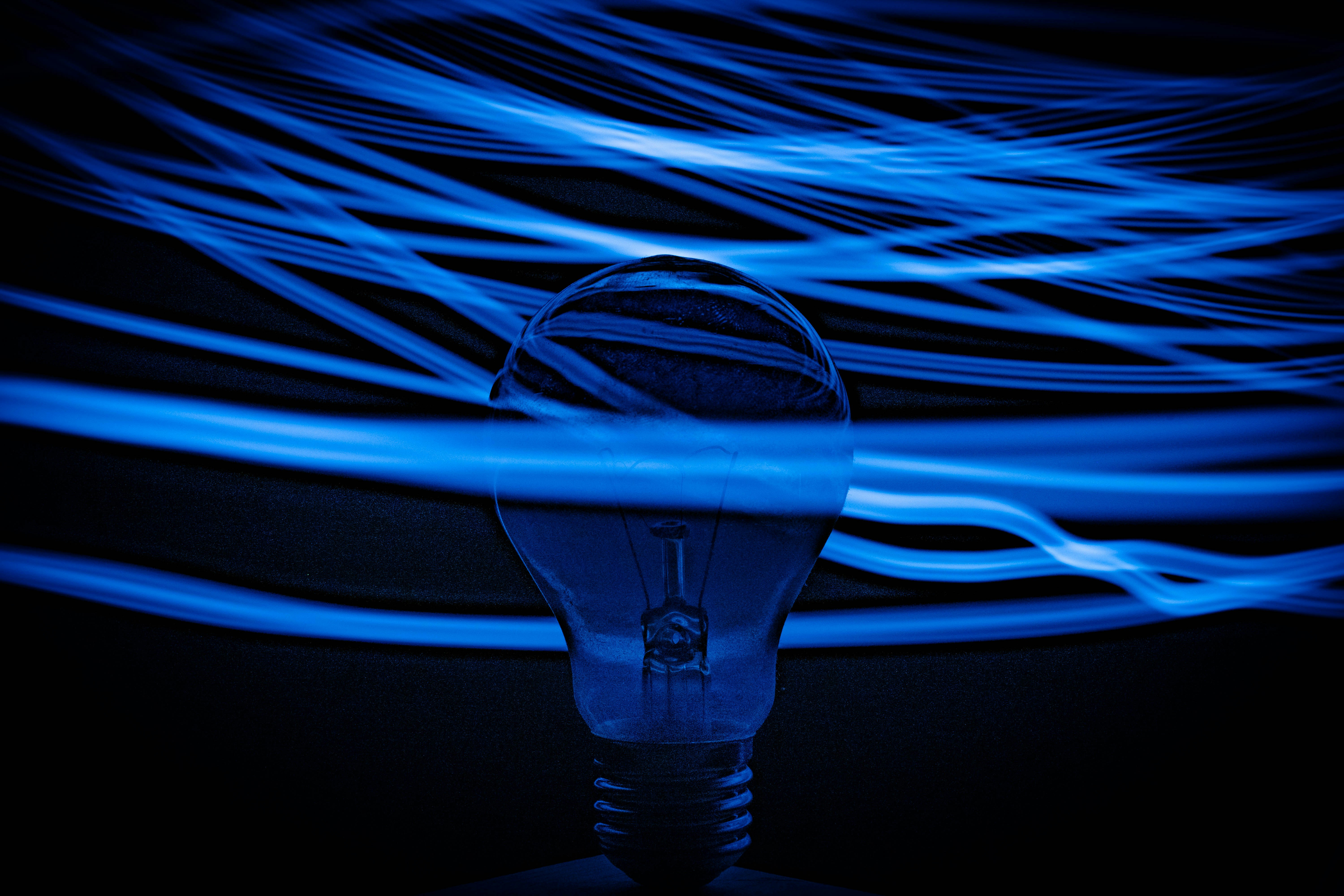 A silhouette stands against a dark background, surrounded by flowing blue light strands.