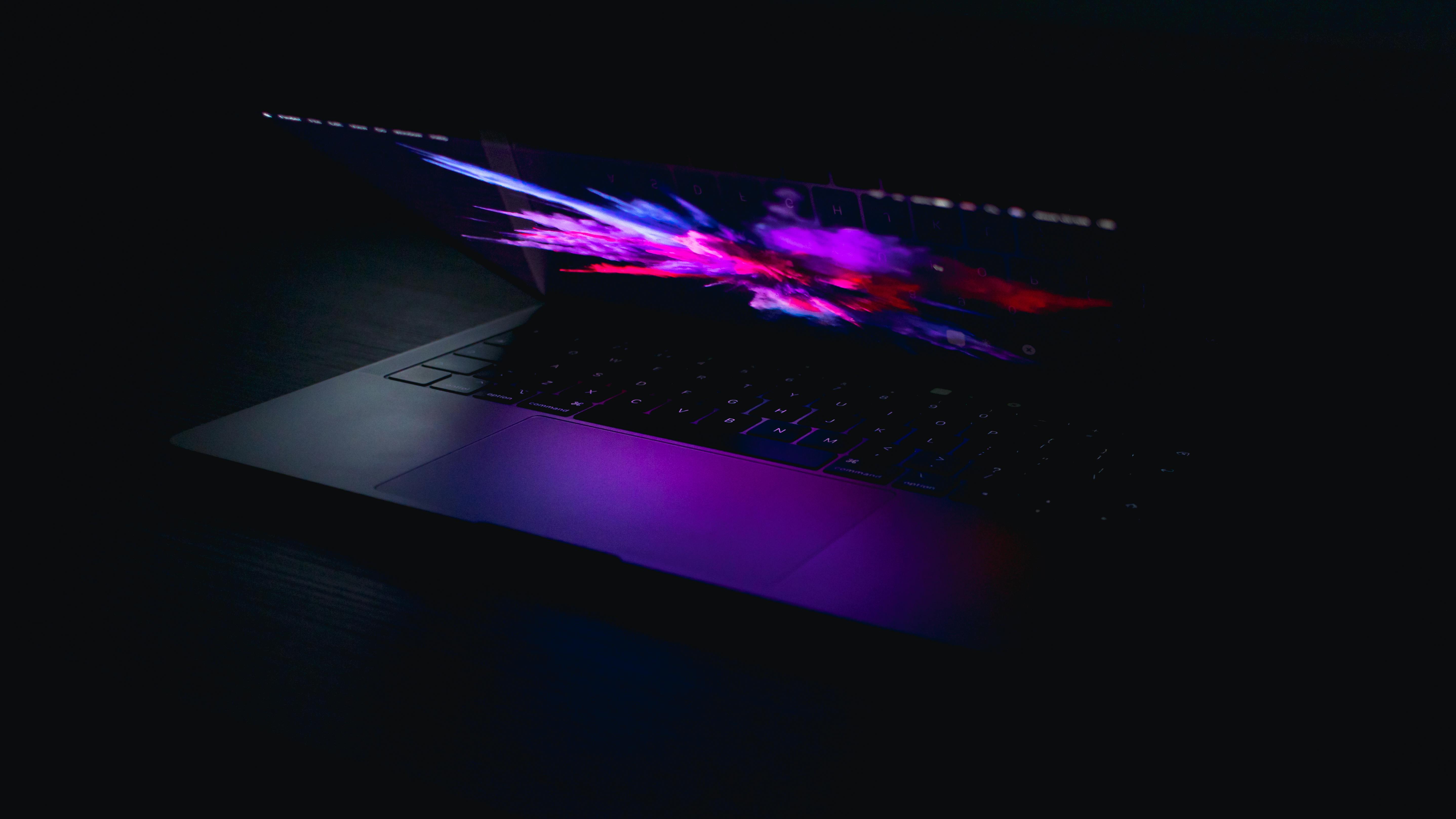 Glowing laptop screen in a dark room with vibrant colors.