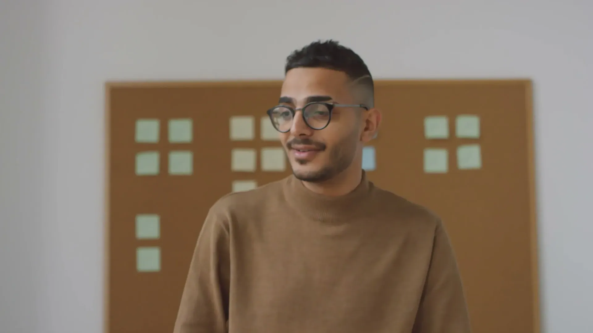 A person wearing glasses and a scarf smiling.