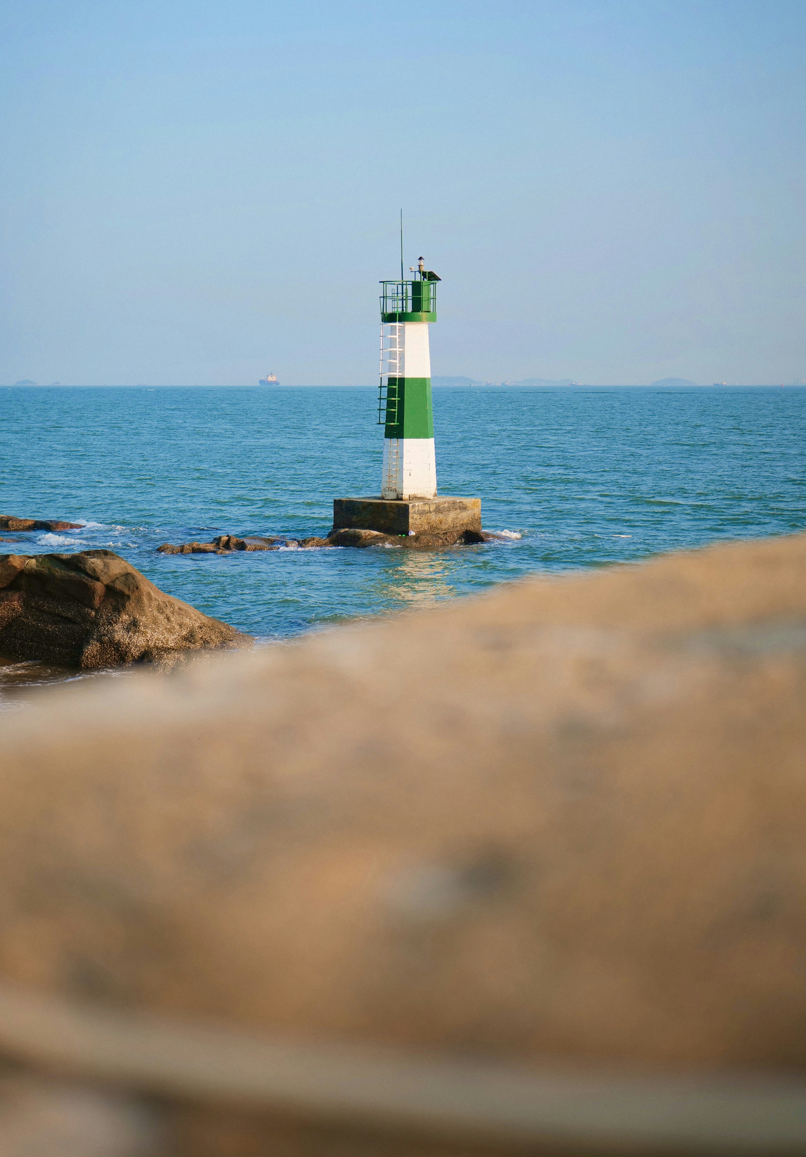 a green and white lighthouse sitting on top of a rock