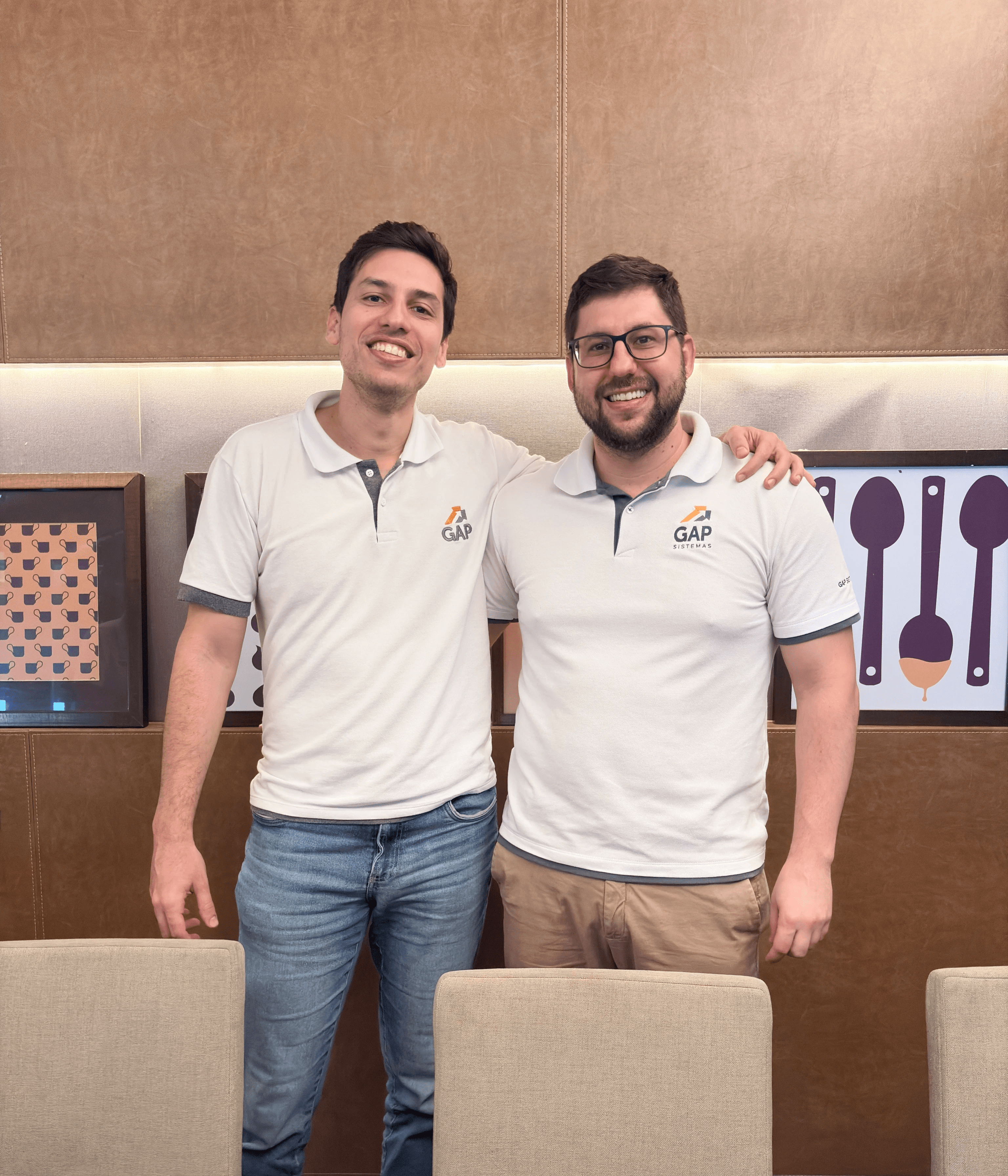 Quatro membros do time da GAP Sistemas, vestindo camisas polo brancas com o logo, sorrindo e posando no stand da empresa em um evento, com o logo da GAP ao fundo.