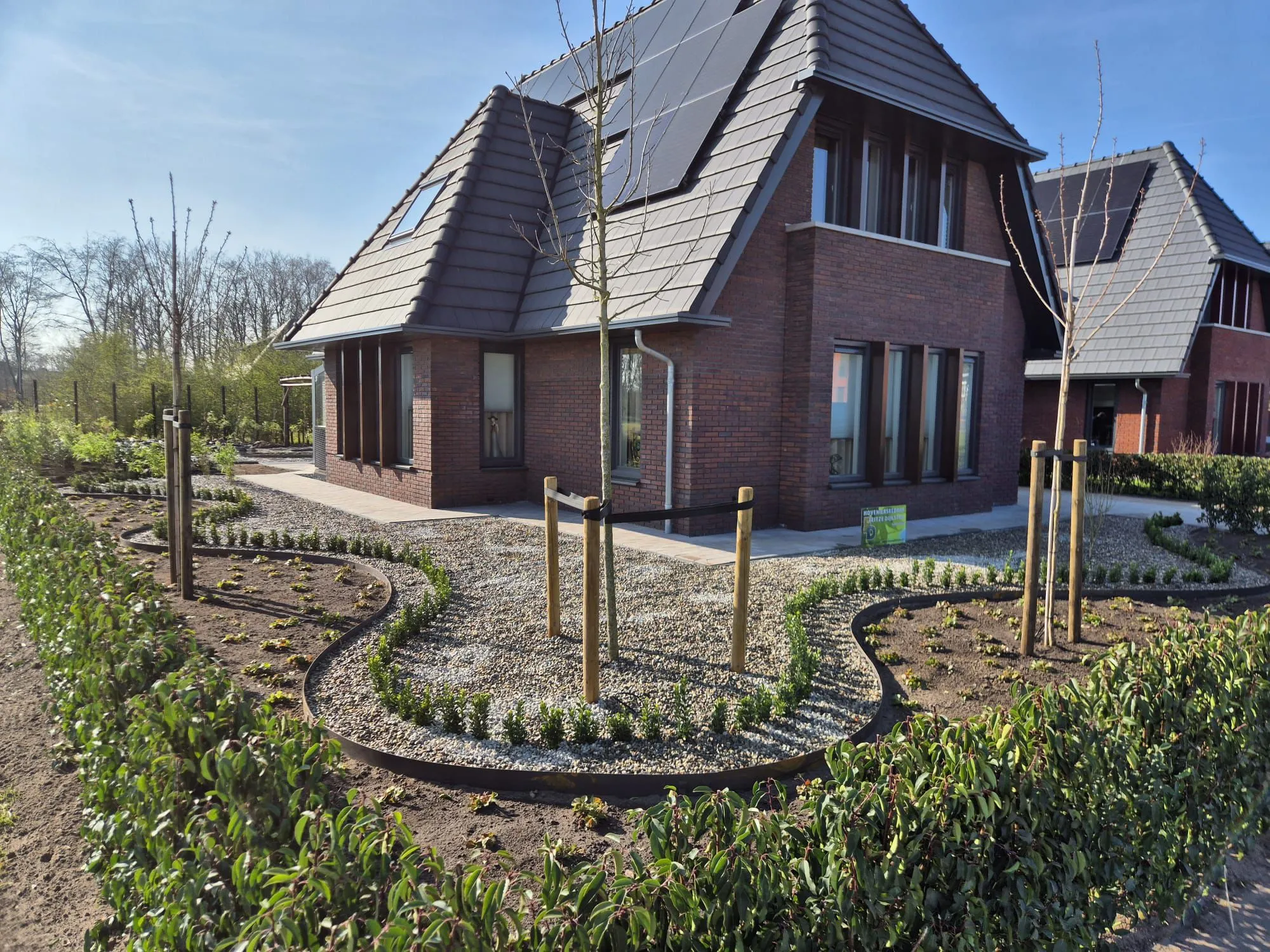 Rustige Japanse tuin met grind, jonge bomen en strakke hagen rond een nieuwbouwwoning in Gorredijk, Friesland.