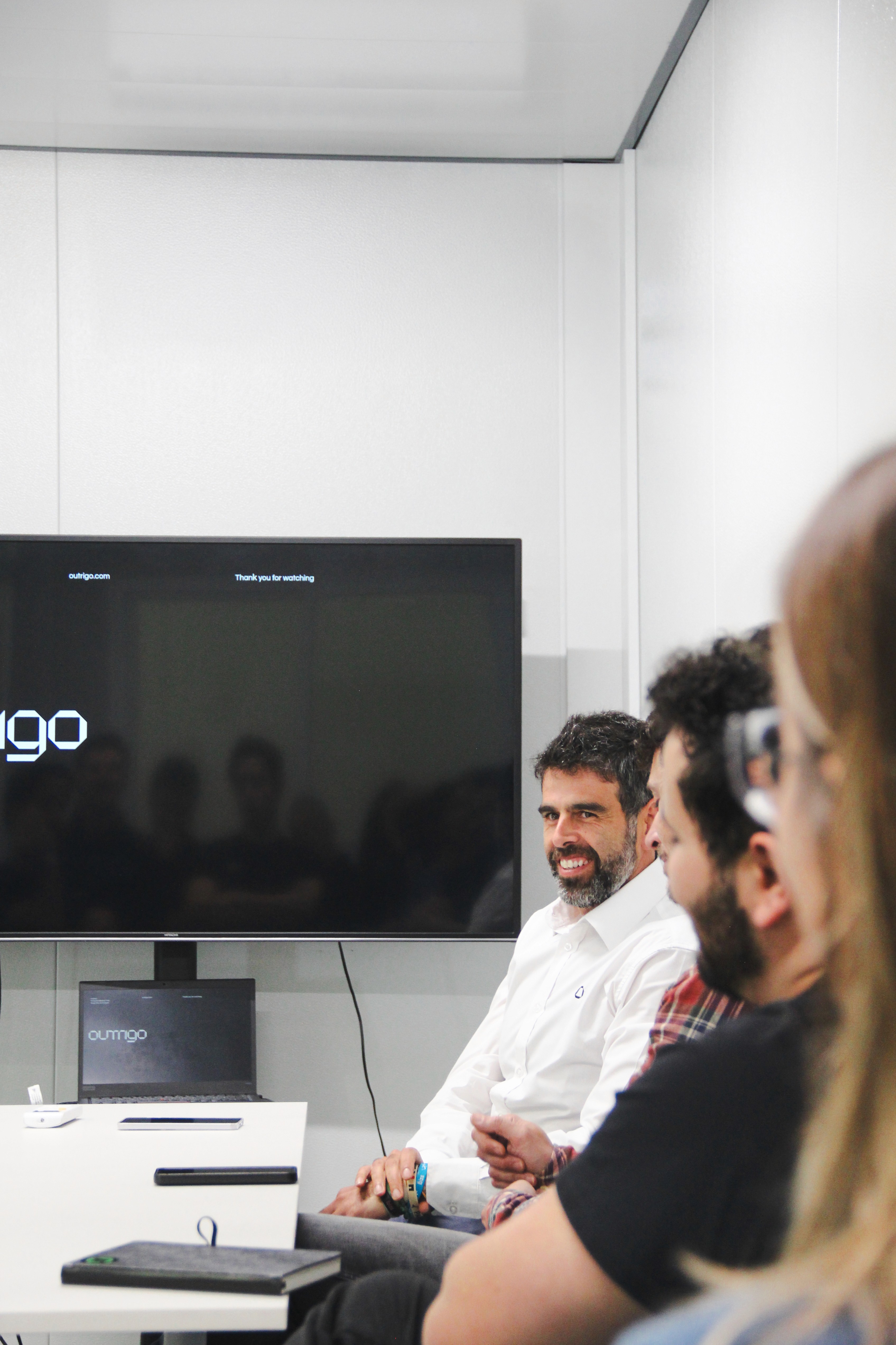 Four diverse professionals collaboratively working on a laptop, with one person pointing at the screen while others observe.