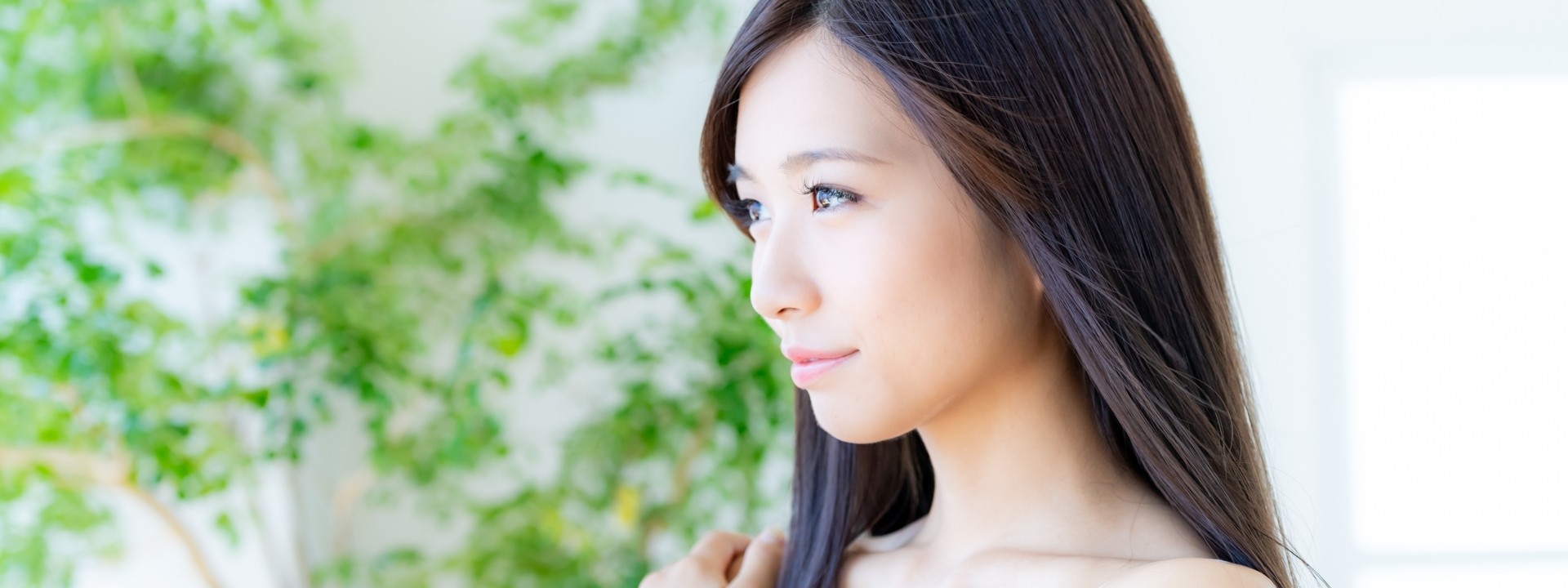 若い女性が自然光の中で横を見つめている様子、美しさと清潔感を感じるポートレート