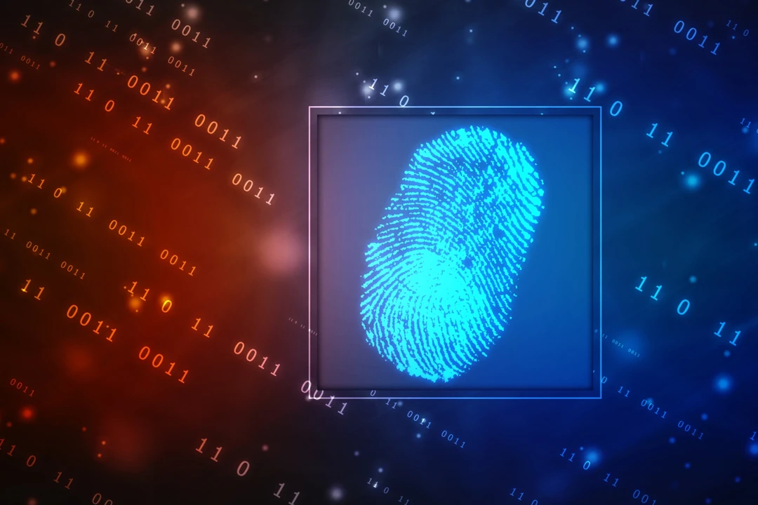A talent recruiter with a soft smile working on her laptop in the office. The angle is on her face so we can't see what's is on the screen. She is wearing a blazer