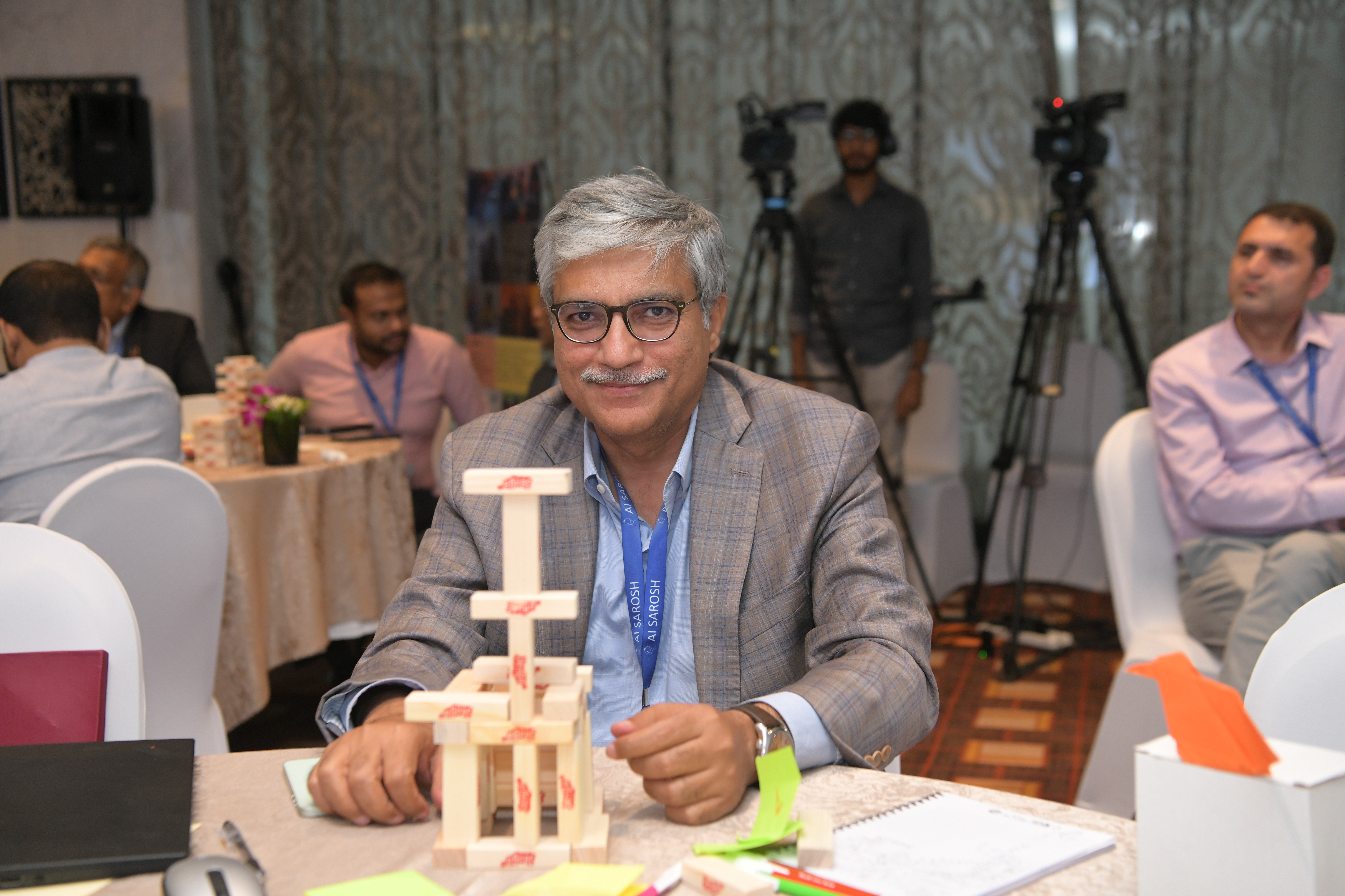 An elderly man who is a participant of CFAW's AI Sarosh Project sitting behind Small Wooden Blocks