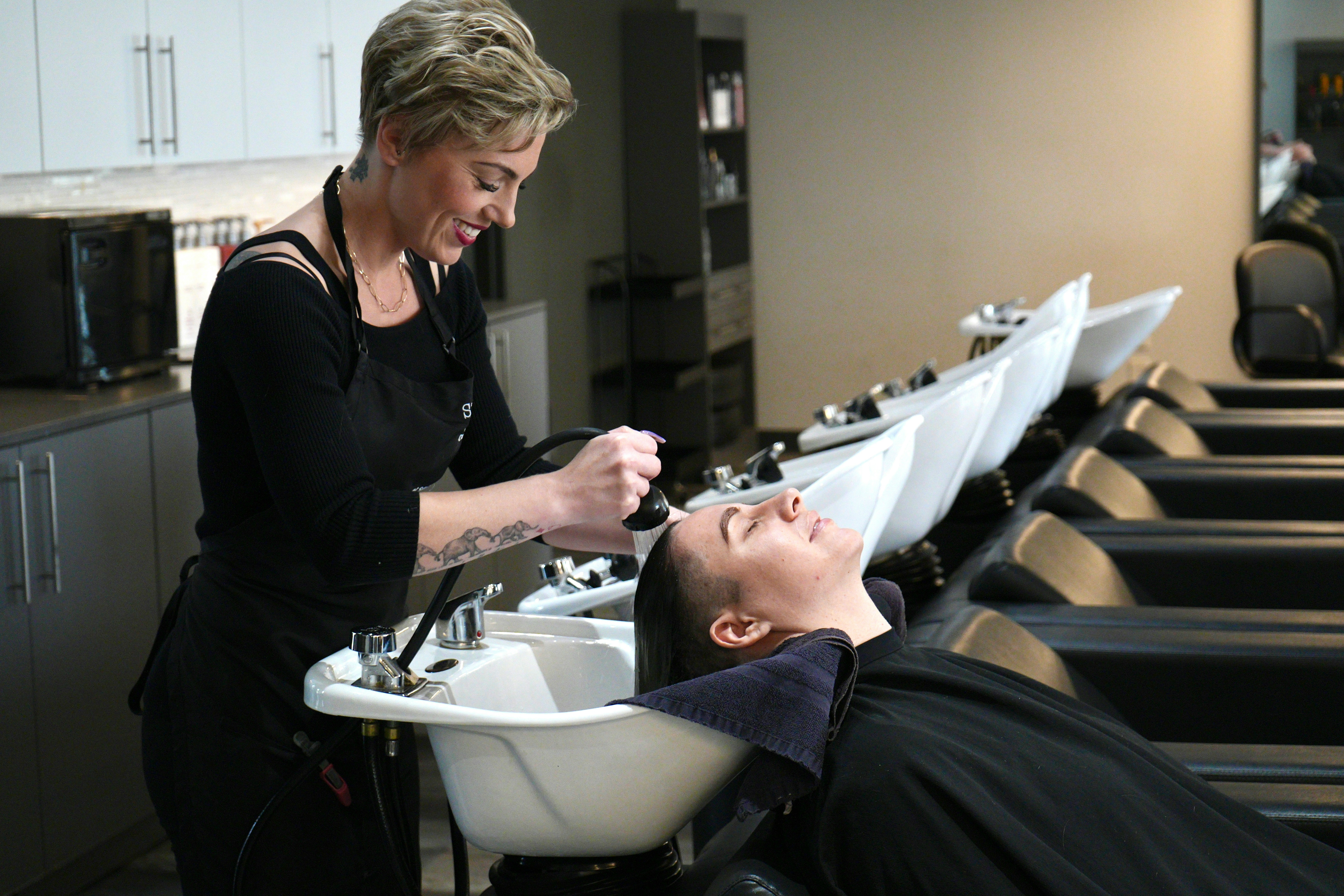 A hairstylist is washing a client's hair at the salon.