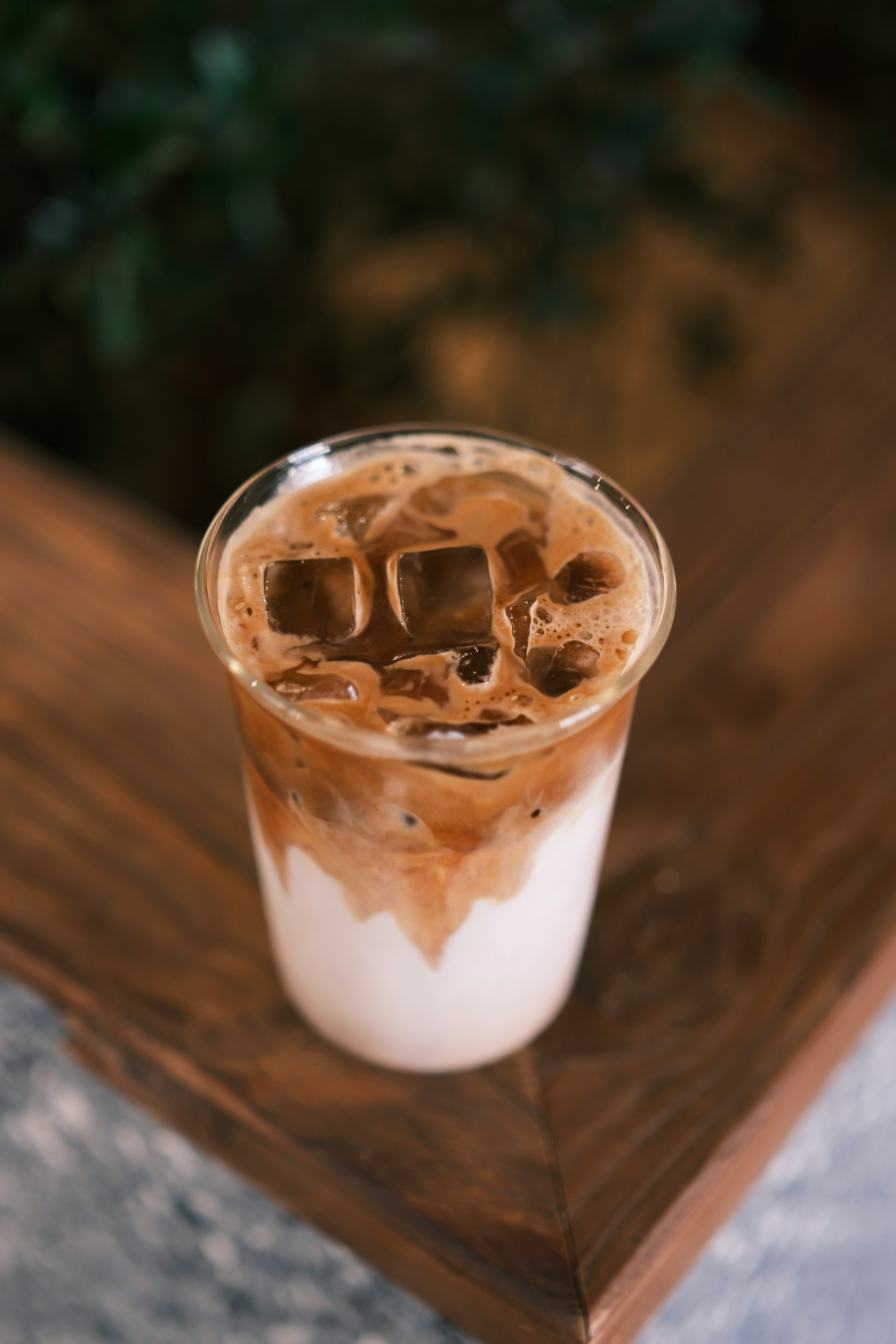 A glass of iced coffee sitting on top of a wooden table