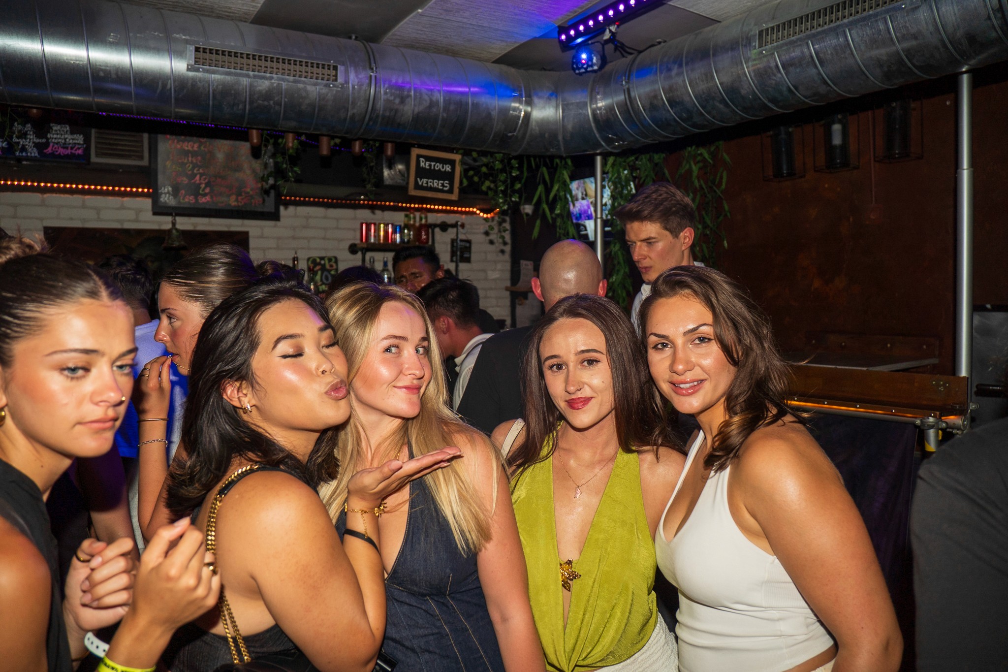 Group of young travelers posing together inside a lively bar during a bar crawl in Nice highlighting social nightlife vibes and group energy in the French Riviera