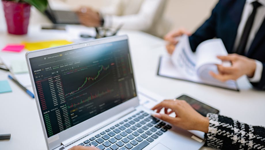 Business team analyzes cryptocurrency market trends using a laptop with graphs and data.