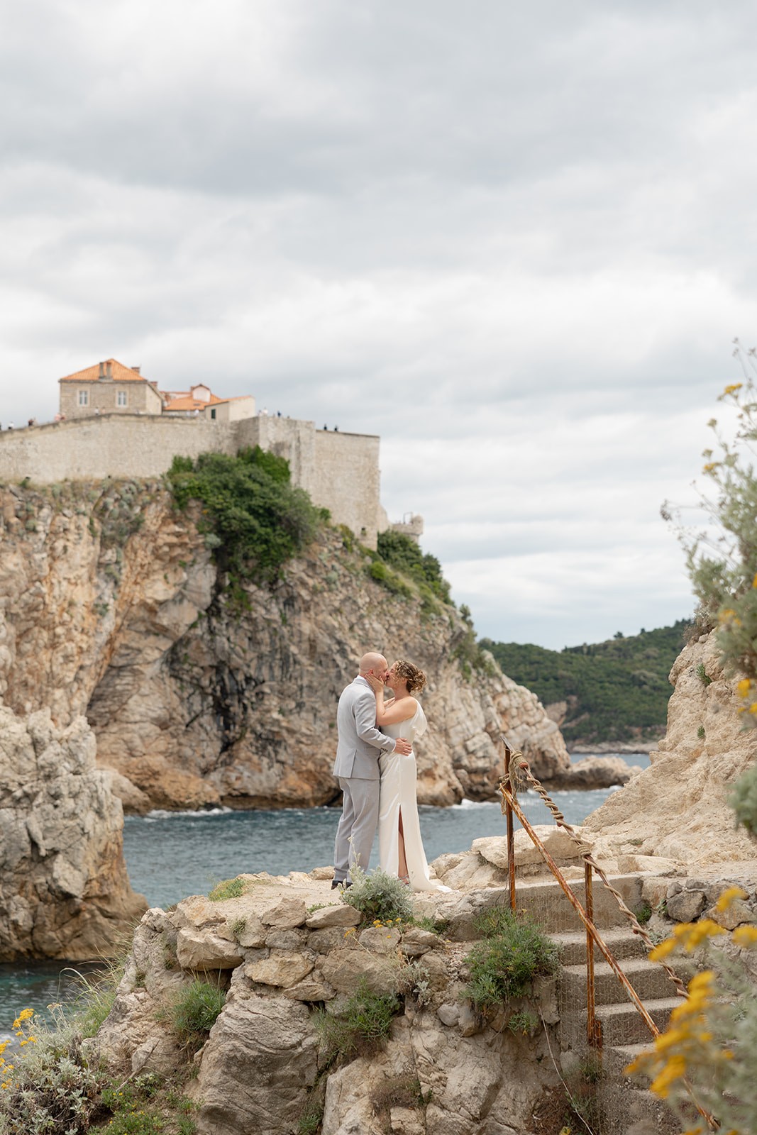 Just married couple posing for a photo in front of two metal gates, doors to the city hall, holding a marriage certificate and a bouquet of flowers in Rijeka, Croatia