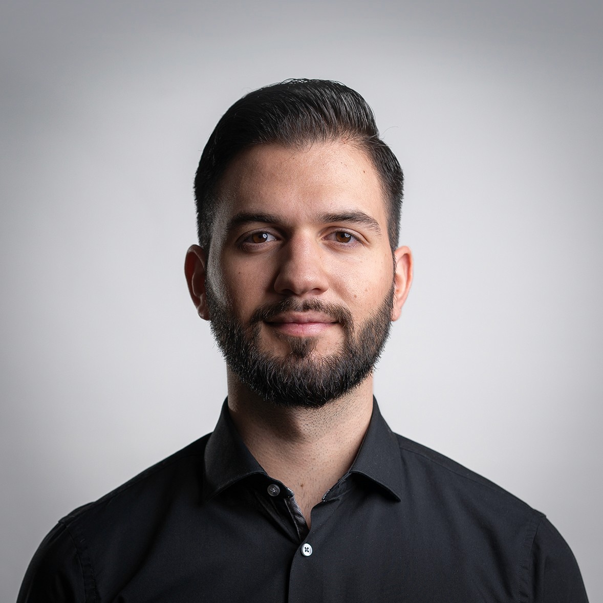 A young person with long, wavy hair sits in front of a plain background, looking directly at the camera.