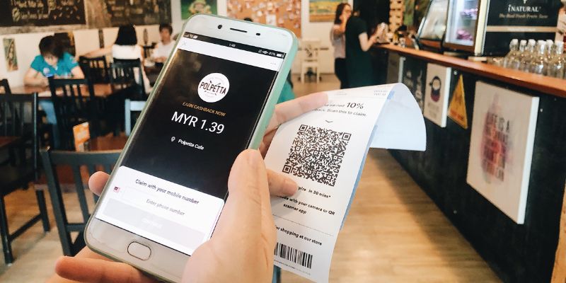 A woman scanning a QR Code on her receipt to redeem Cashback