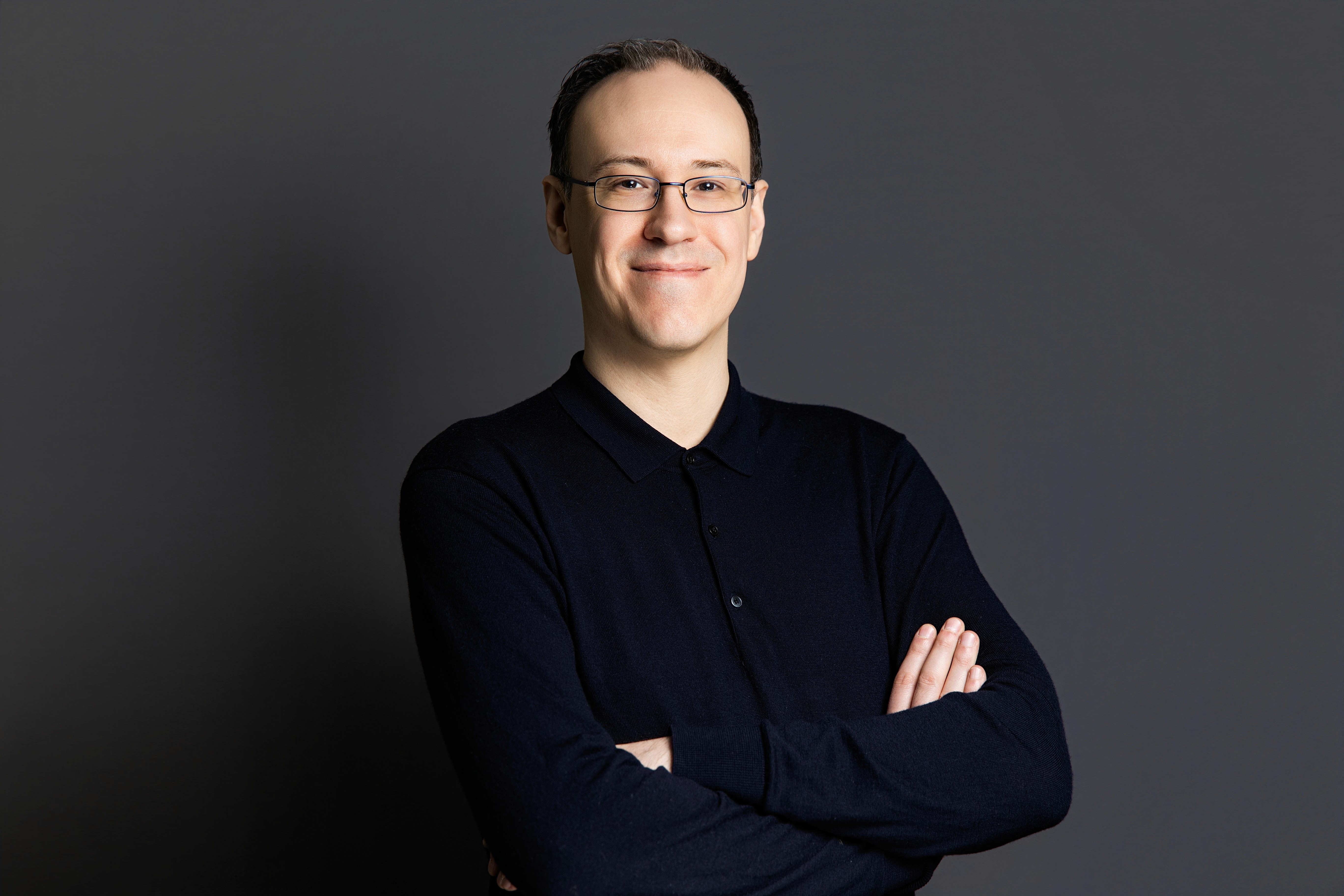 A woman with straight blonde hair wearing a light colored sweater looks away.