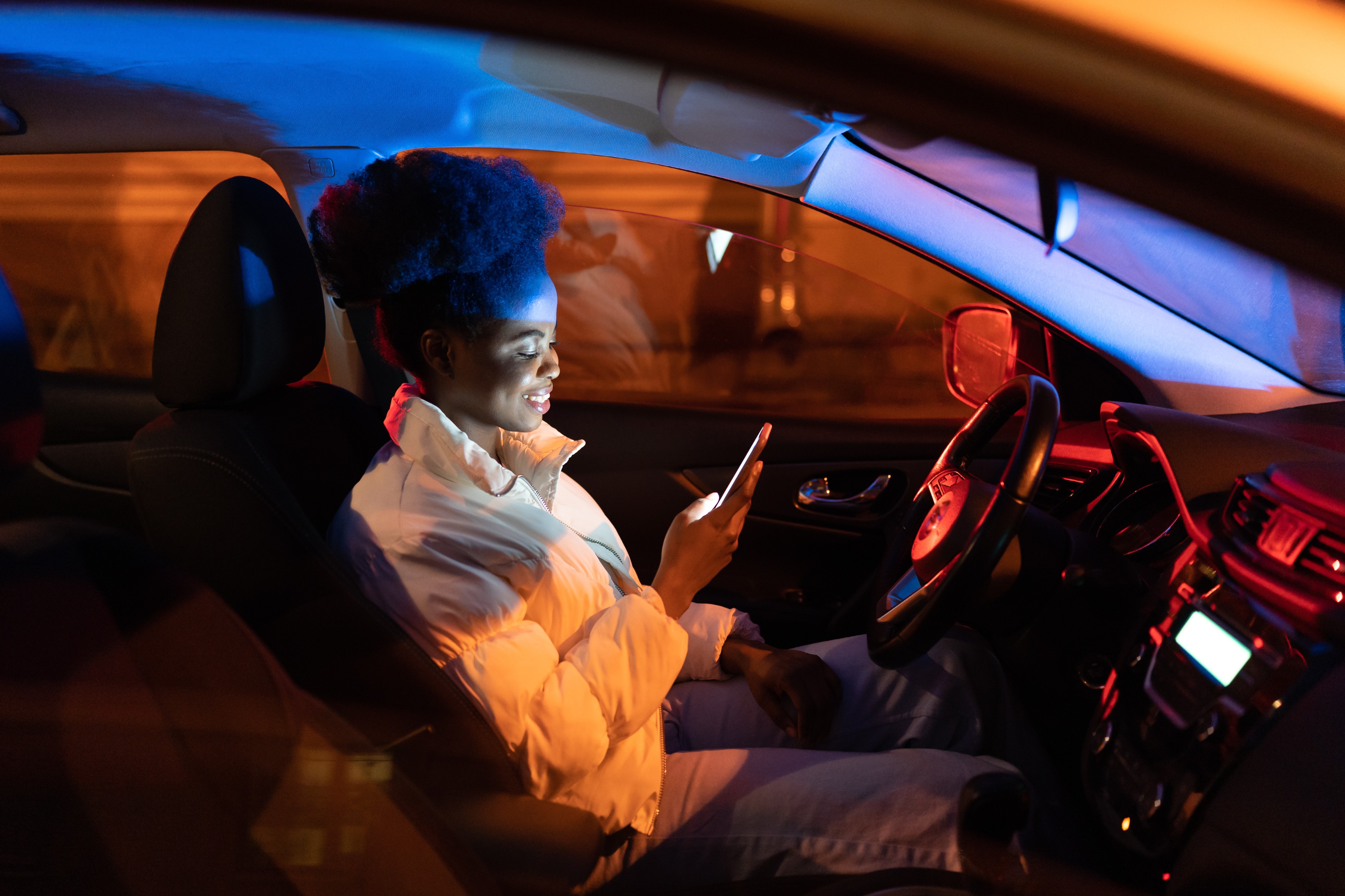 Woman using phone in car at night