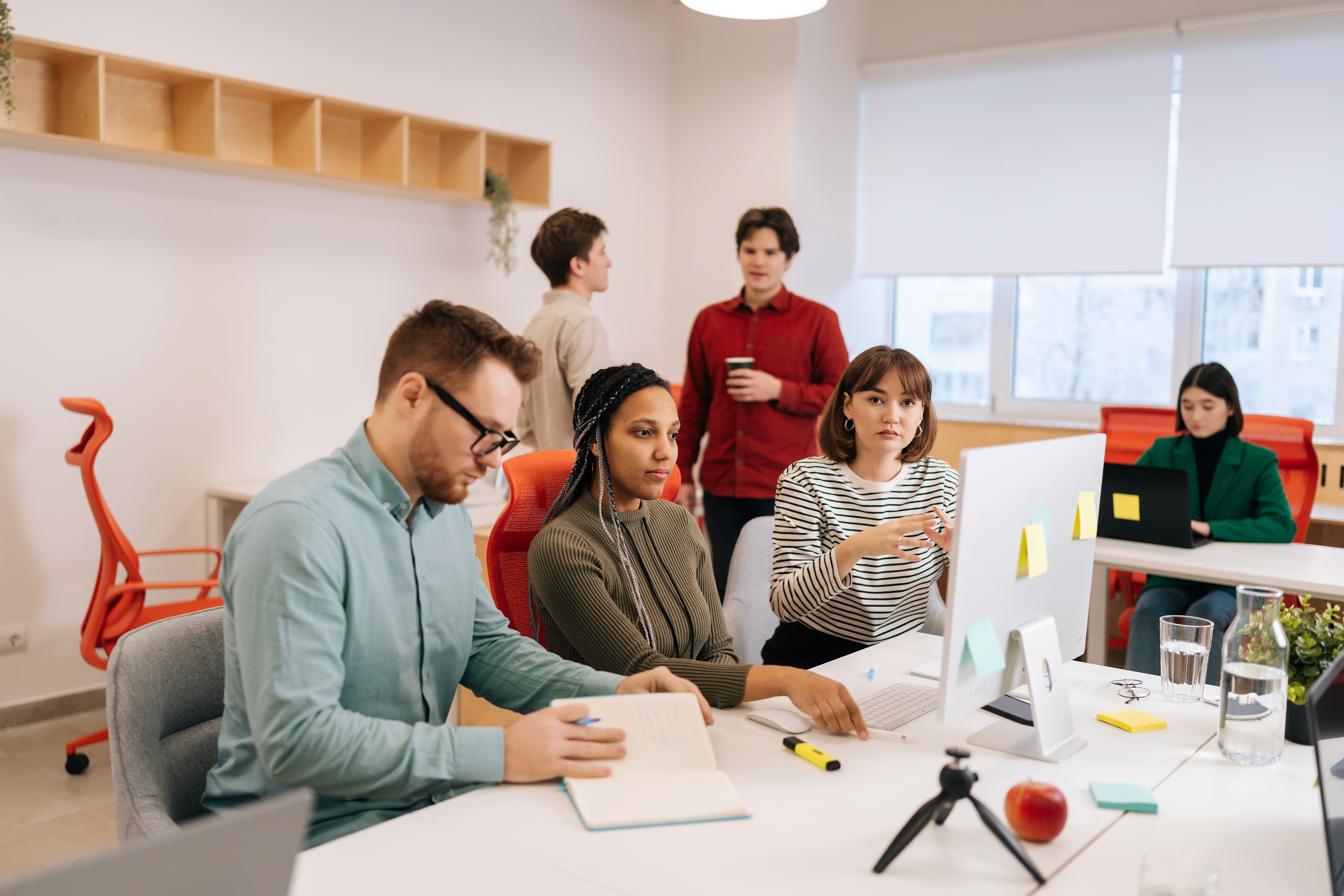 Gray‑haired man in a blazer working on a laptop at a desk.