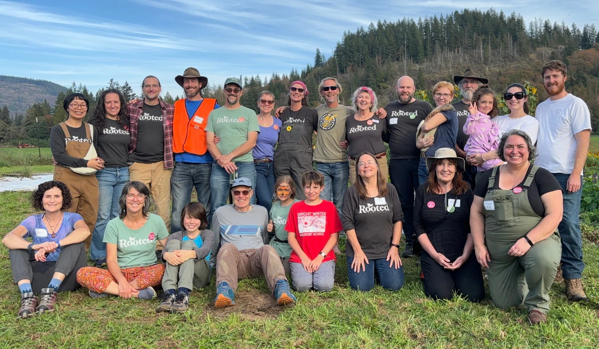 Future neighbors and families pose together in a field during a Rooted Northwest community gathering.