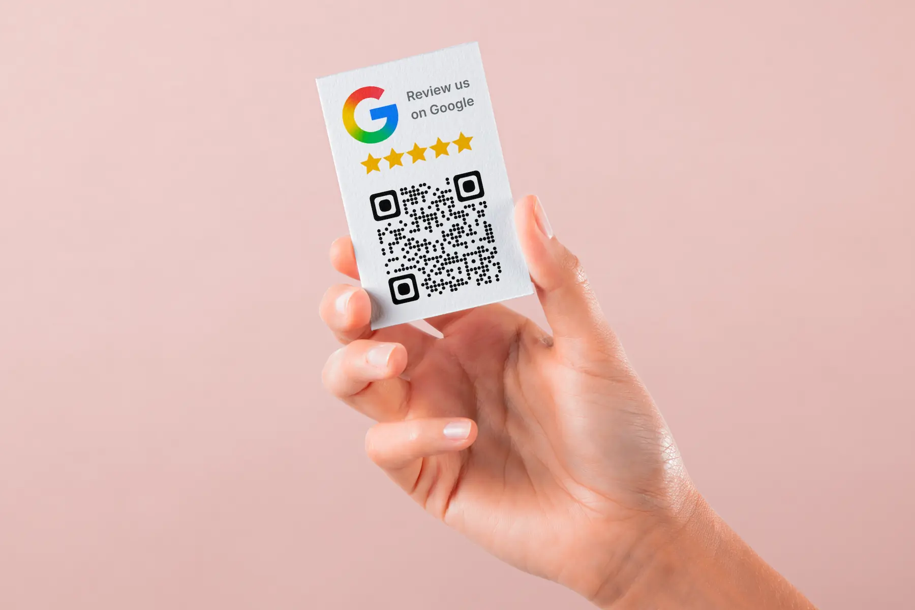 A hand holding a business card showing a QR code to leave a review on Google.