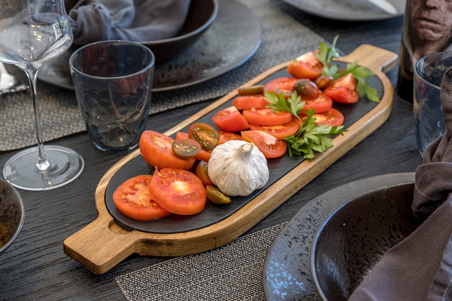 Close-up of a curated tomato platter with herbs and garlic on a luxury outdoor dining table at Can Nemo.