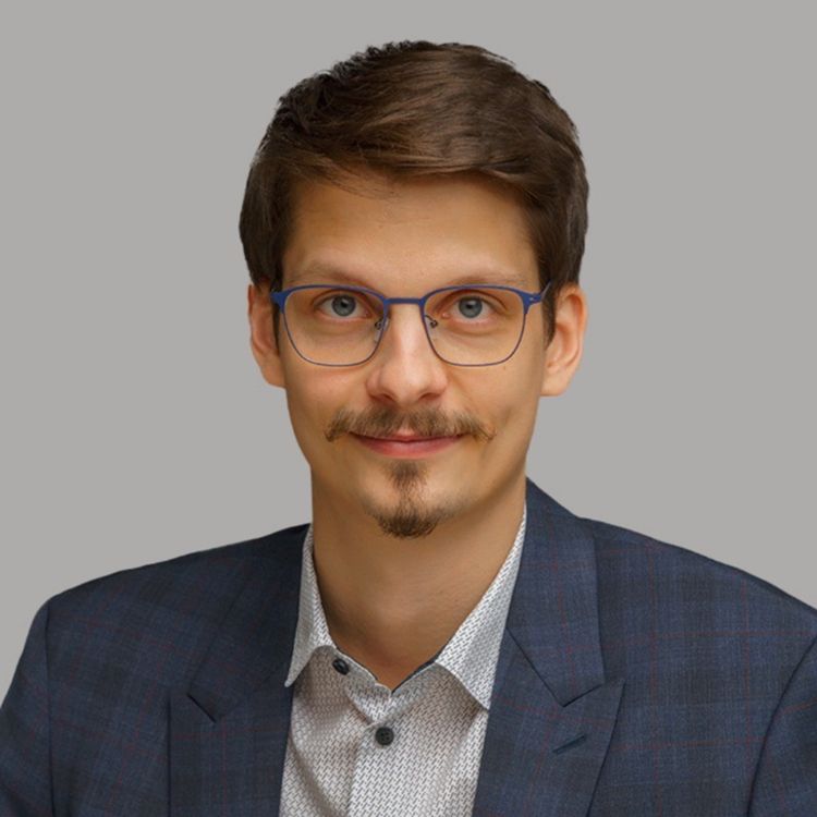 Brown-haired man with a goatee and blue glasses