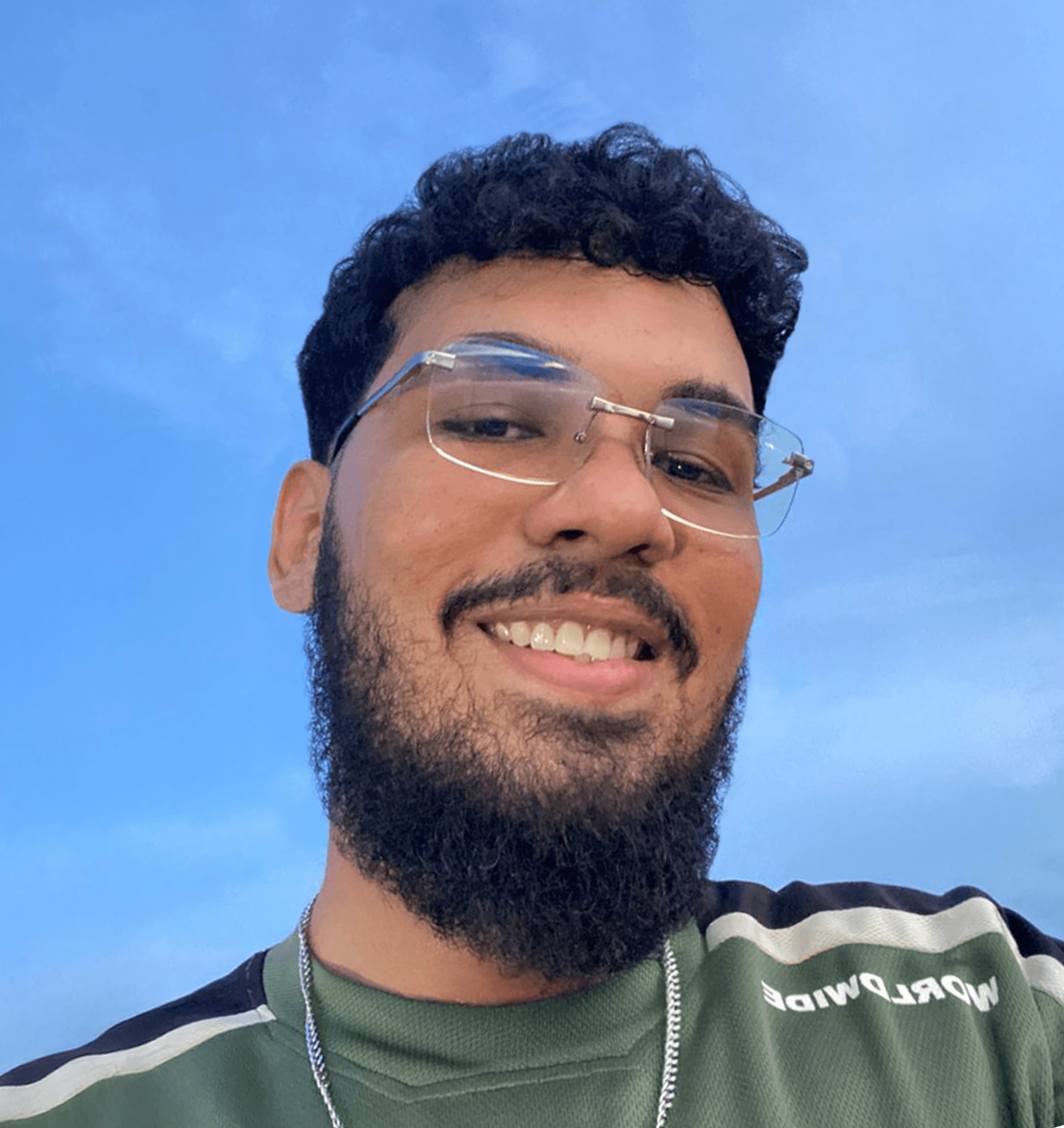 A person with wavy light hair stands facing slightly to the left, wearing a striped shirt against a neutral background.