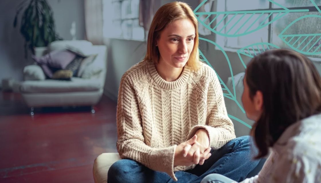 Two women talking in a well lit room with large windows