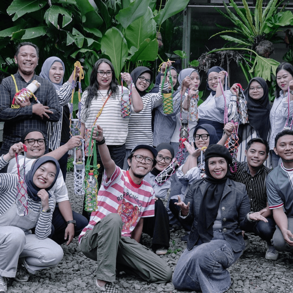 Smiling young woman with long hair standing against a dark green background, holding a finger to her chin.