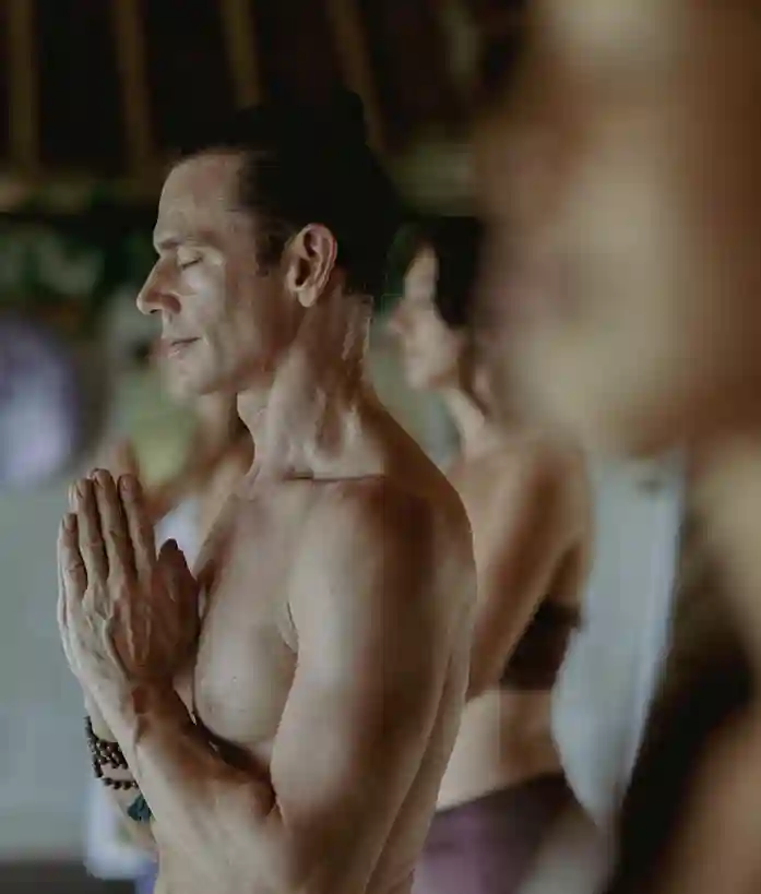Male yoga student with hands in prayer position (Anjali Mudra) practicing mindfulness meditation.