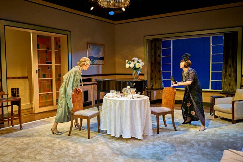 Two women in 1920s outfits arguing across a dining table in Fallen Angels.
