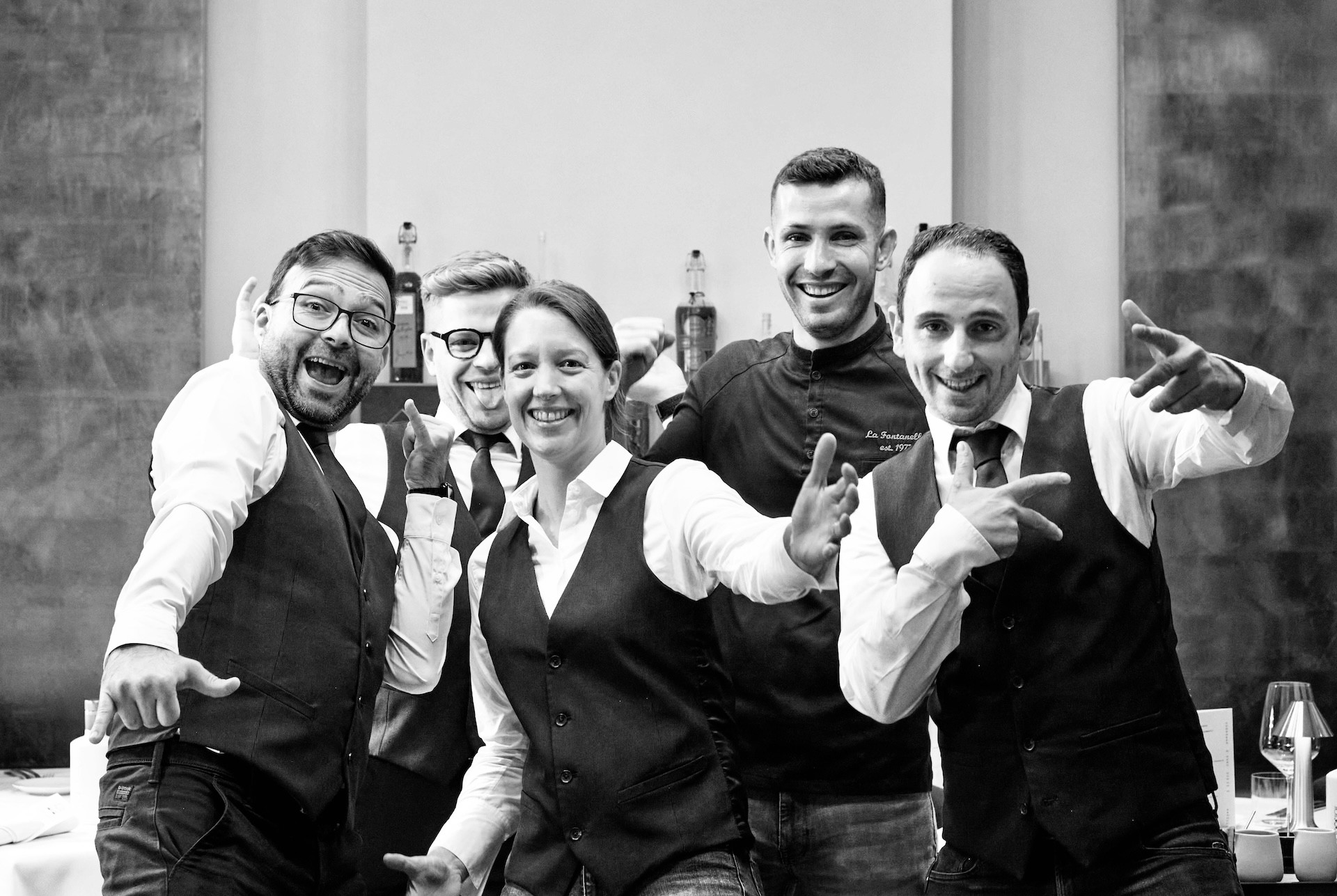 Joyful and enthusiastic La Fontanella team members posing playfully in the restaurant