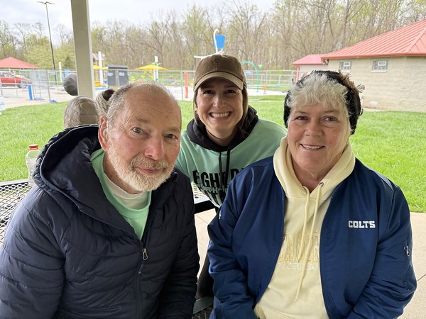 A woman in a red top sits at a desk, talking to someone out of view in an office setting.