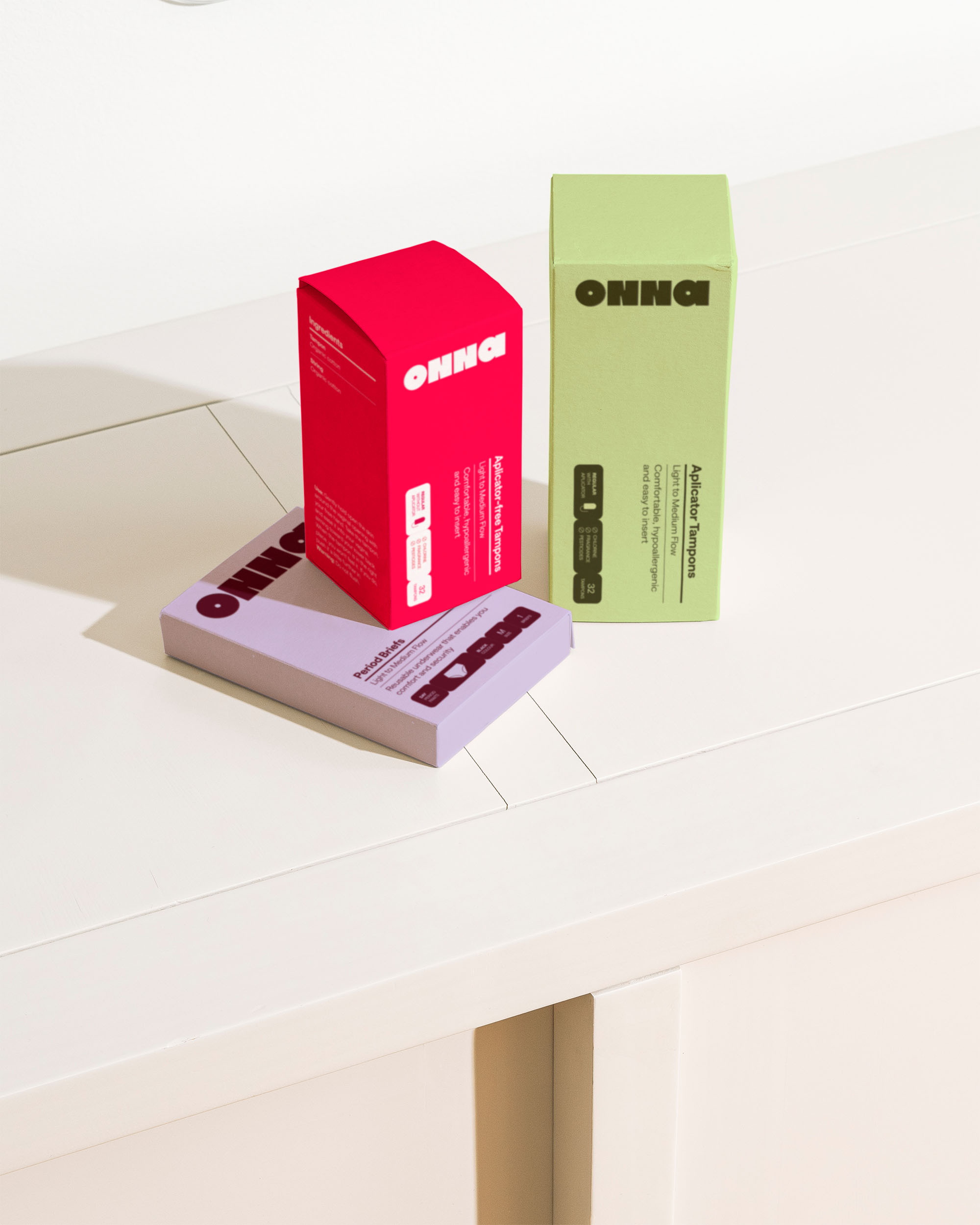 Product packaging suite in red, lime green, and lavender arranged on white surface