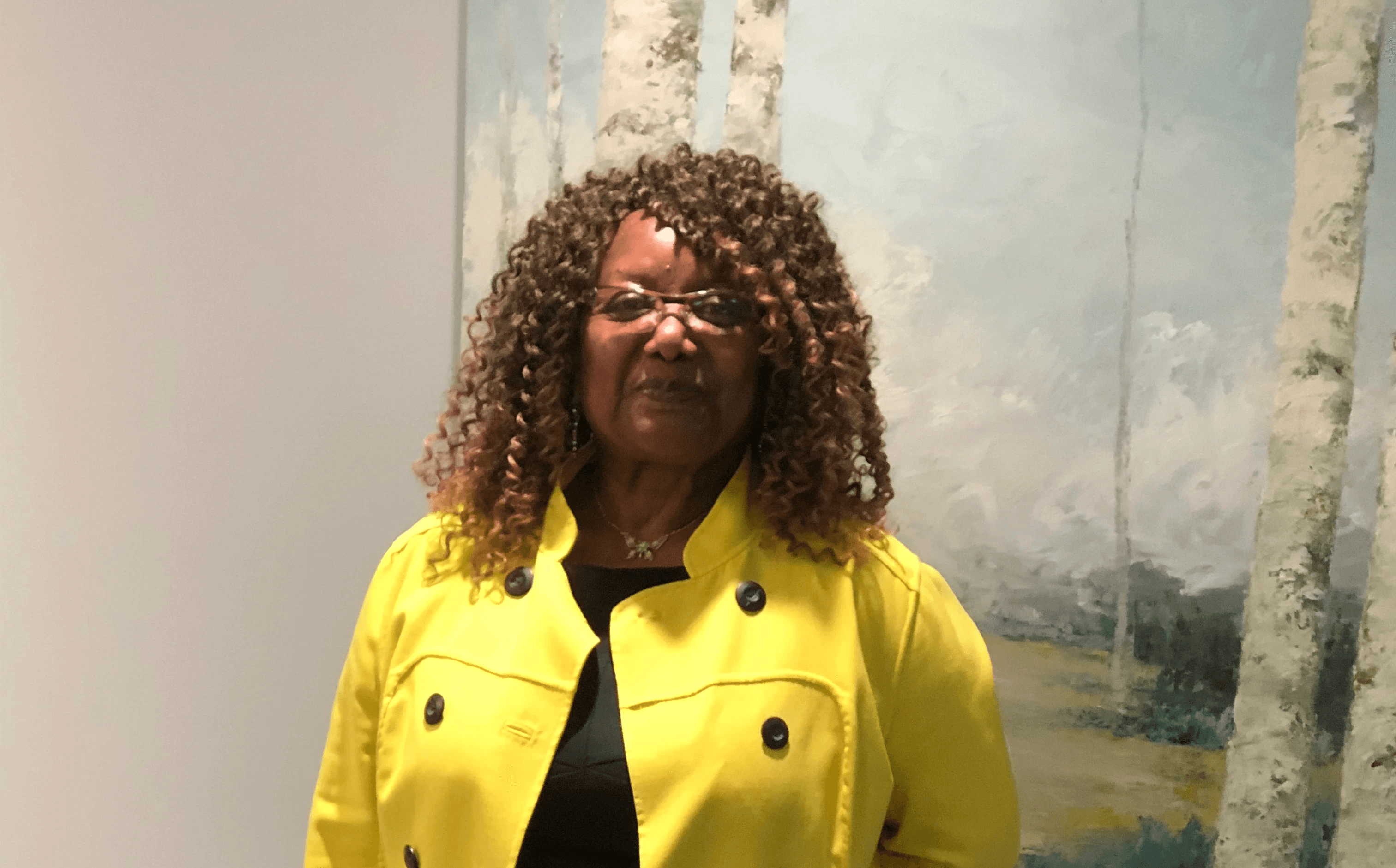 woman in black blazer covering her face with her hand