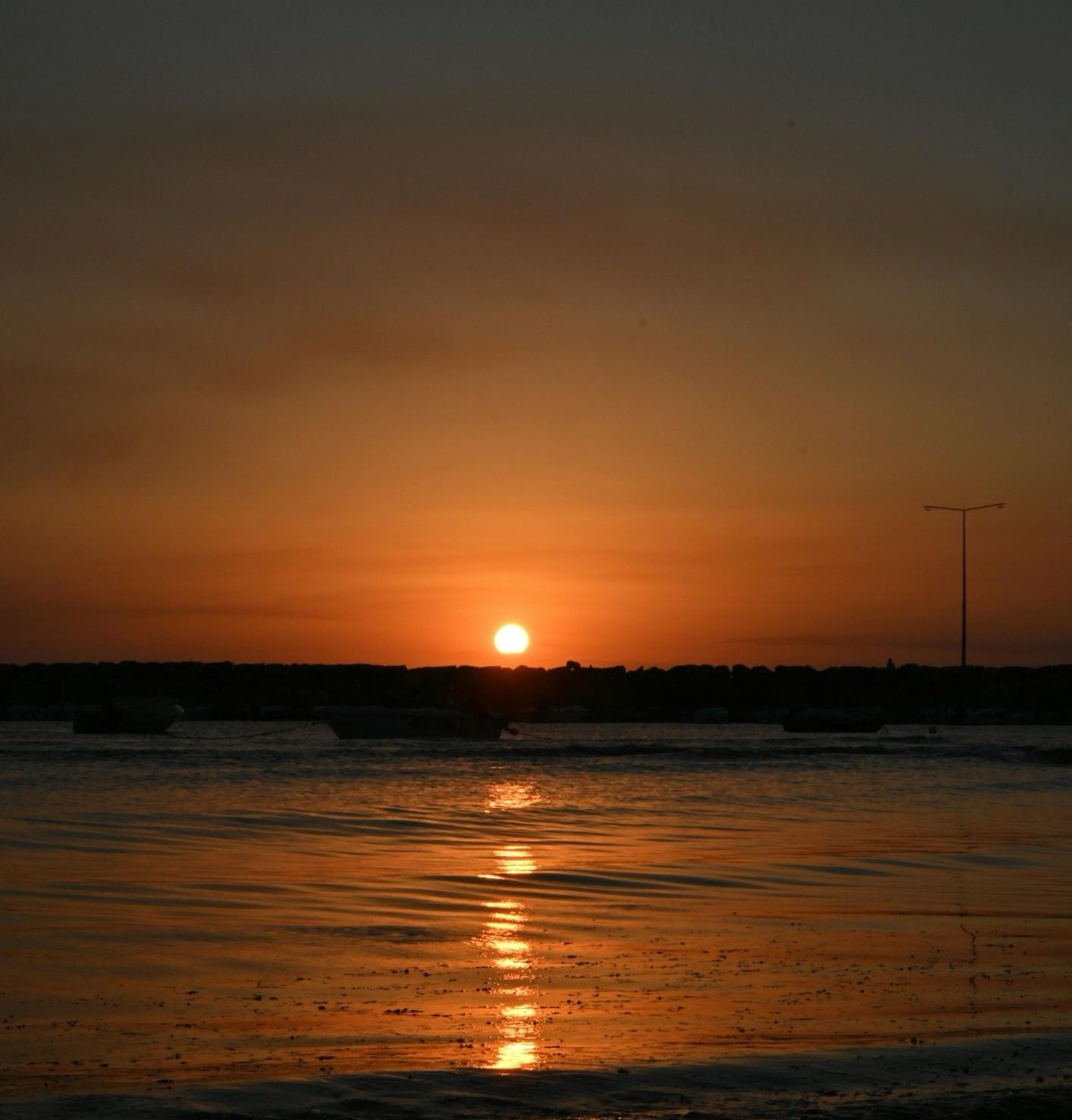 Dimly lit room with sunlight filtering through curtains, casting shadows on a green marble table with a single plate of pasta in the center.