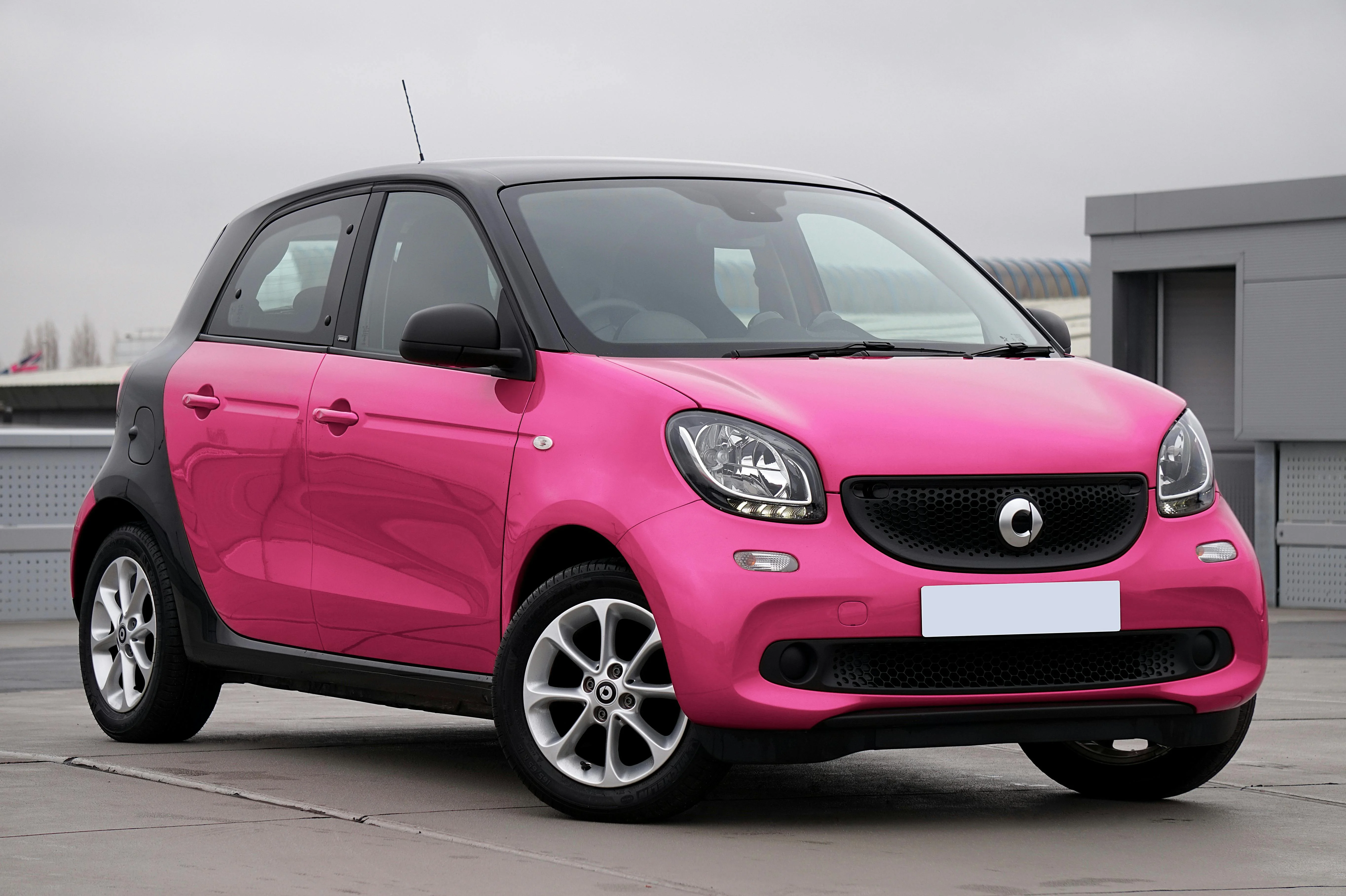 Petite voiture citadine rose stationnée en milieu urbain.