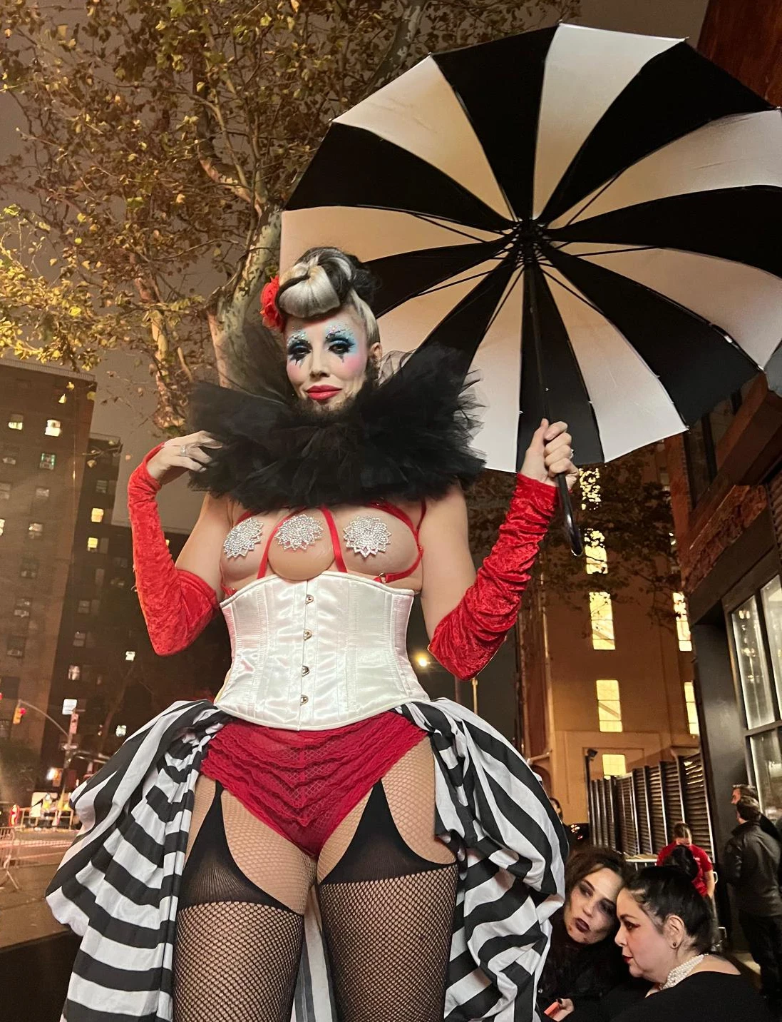 Dark circus performer with a striped umbrella, corset and ruffled skirt