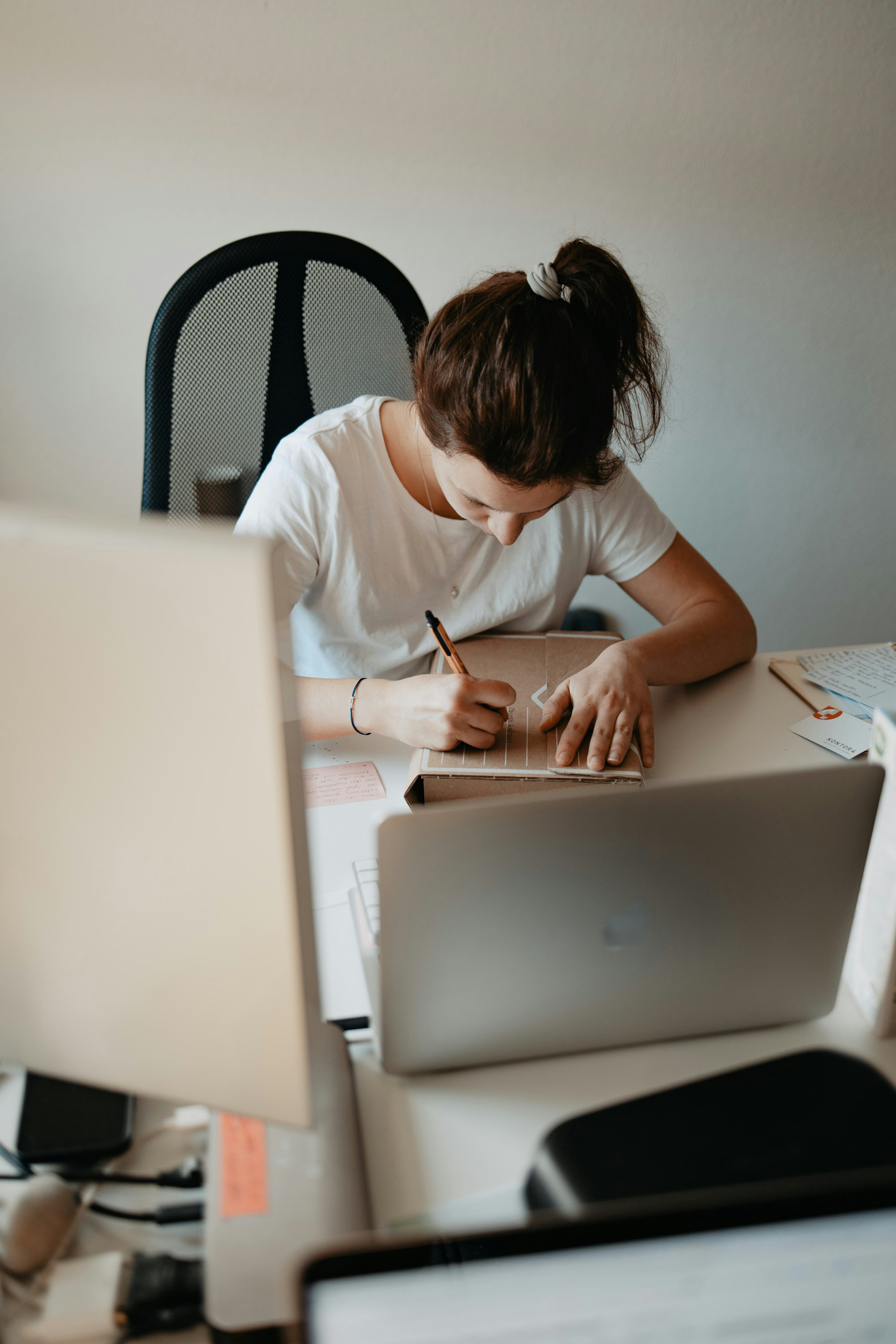 woman in white shirt writing on white paper