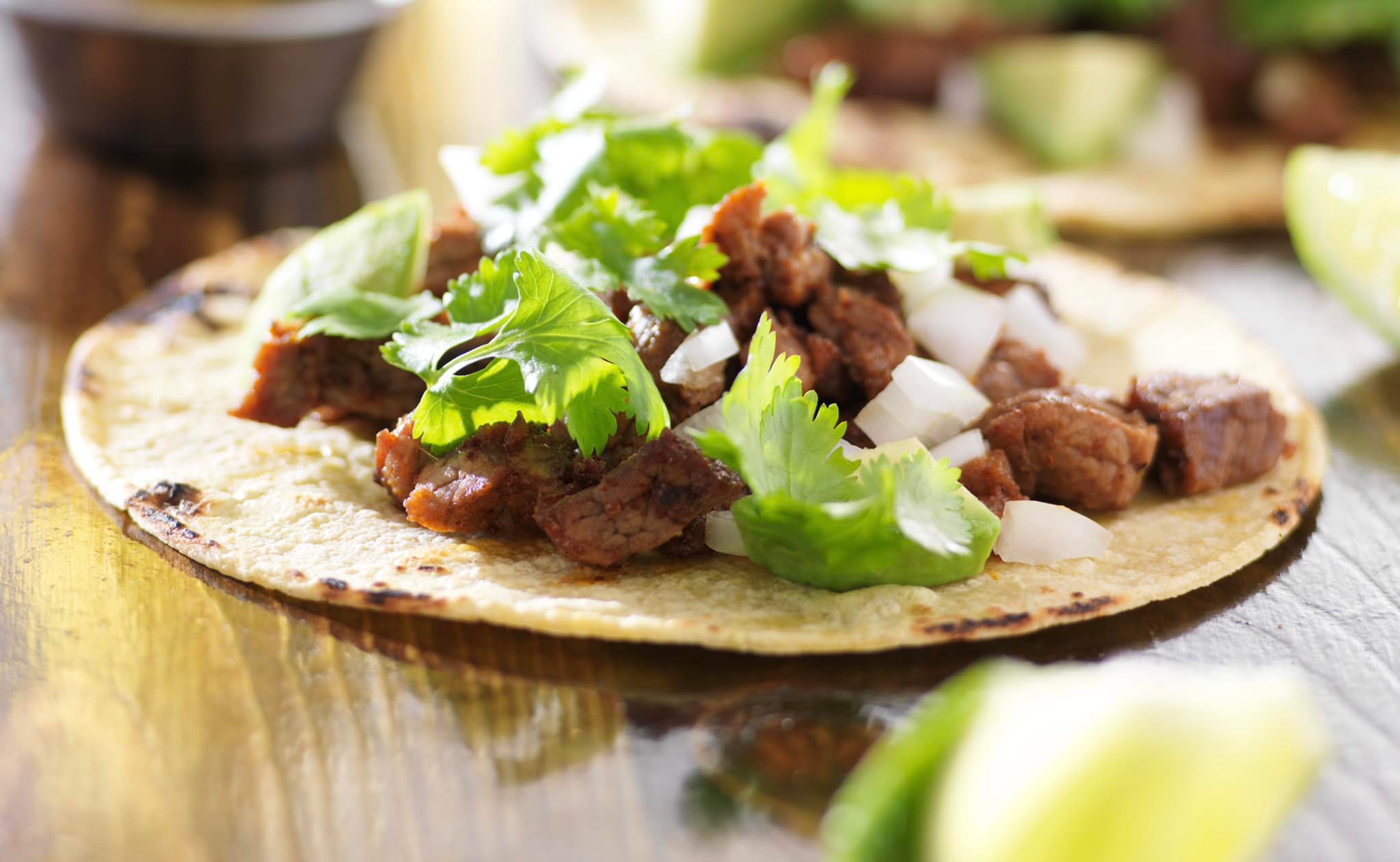 Casa del Sol's famous Birria Tacos: tender, slow-cooked beef wrapped in grilled corn tortillas with melted cheese, served alongside a flavorful consommé for dipping.