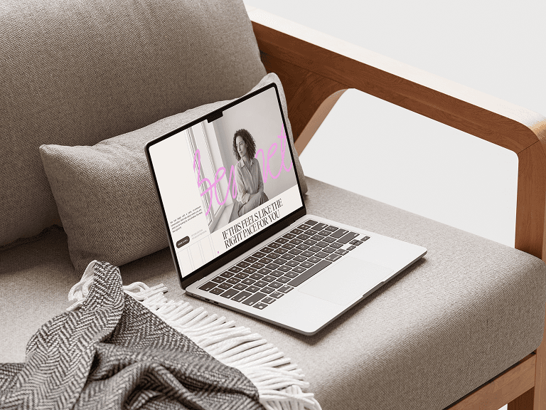 Laptop on a sofa displaying a webpage with a woman.