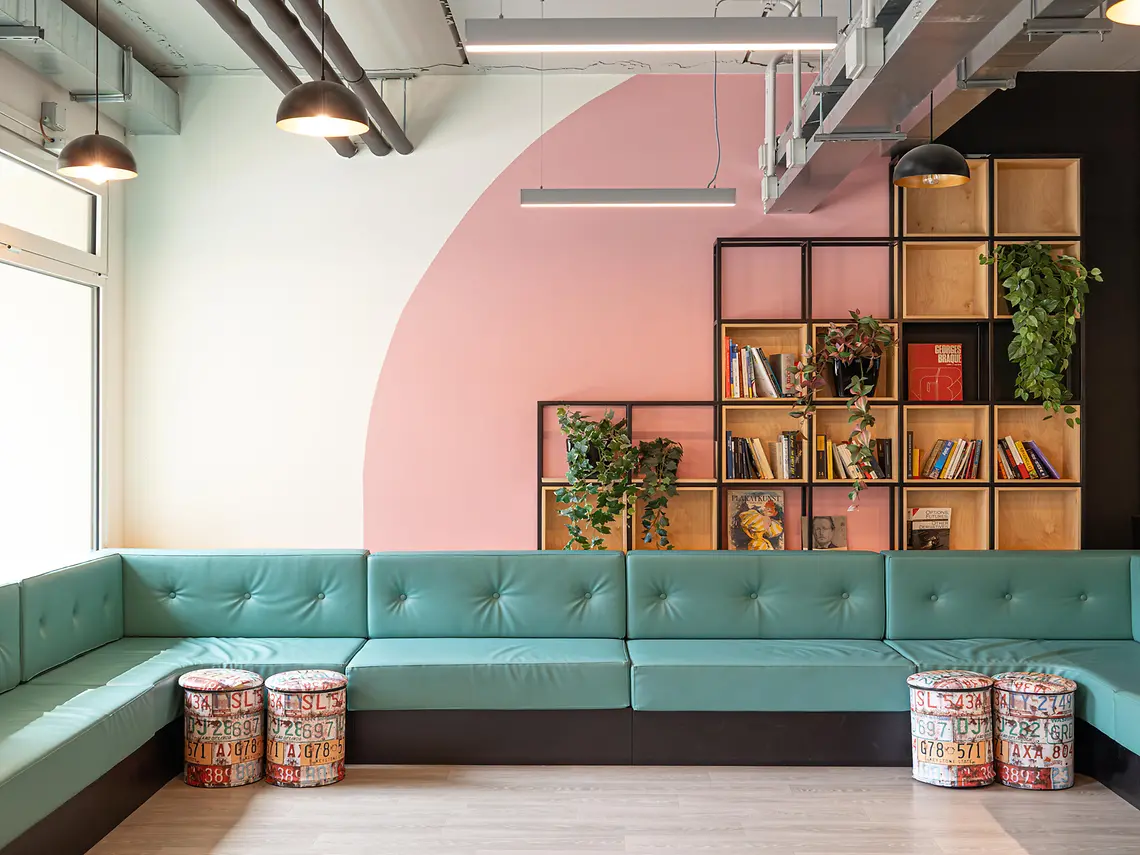 Communal student lounge with sofa seating, bookshelves and plants in Bologna student accommodation
