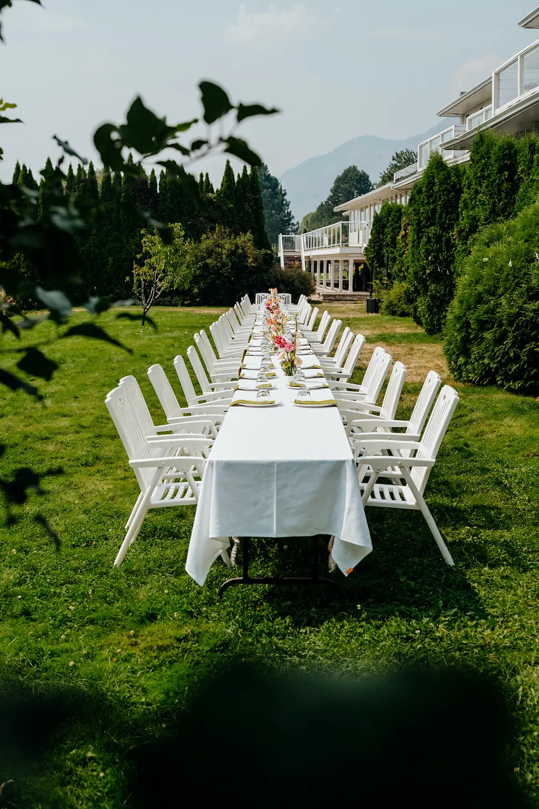 Long outdoor banquet table with white chairs and floral centrepieces beside South Thompson Inn.