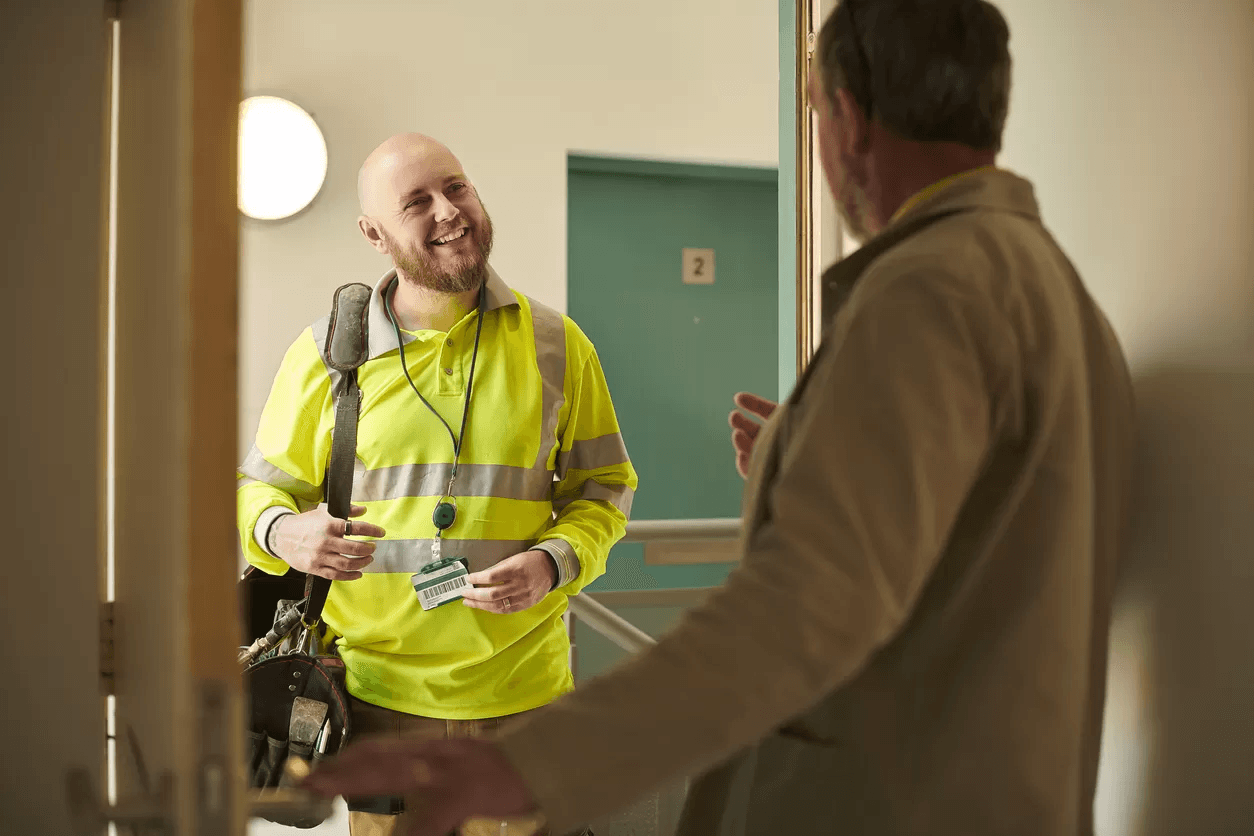 Image of two men stood at a door, smiling and talking